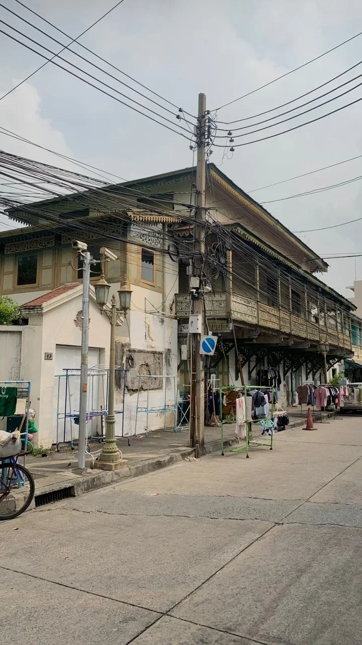 A street scene with an old building, utility pole with multiple wires, street lamps, and clothes hanging outside to dry.