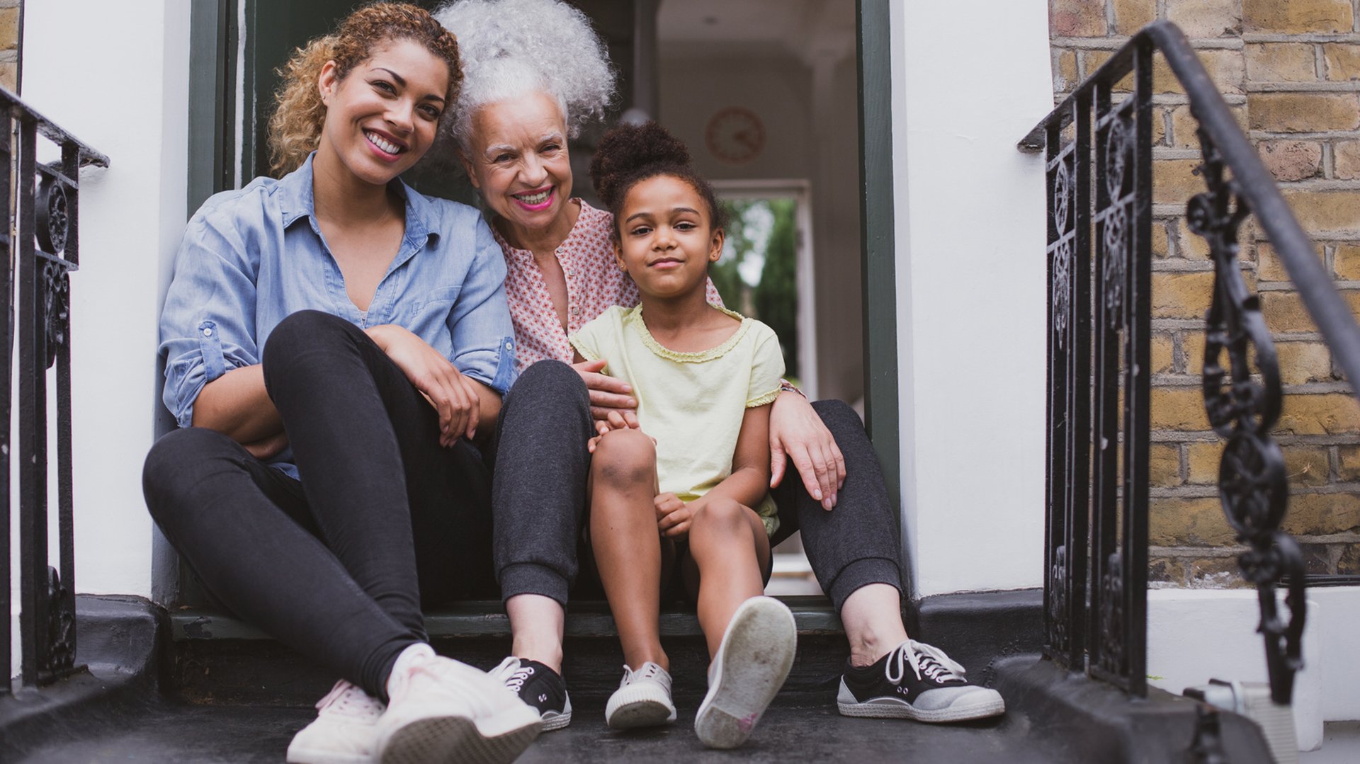 Grandmother, daughter, granddaughter in front of home.