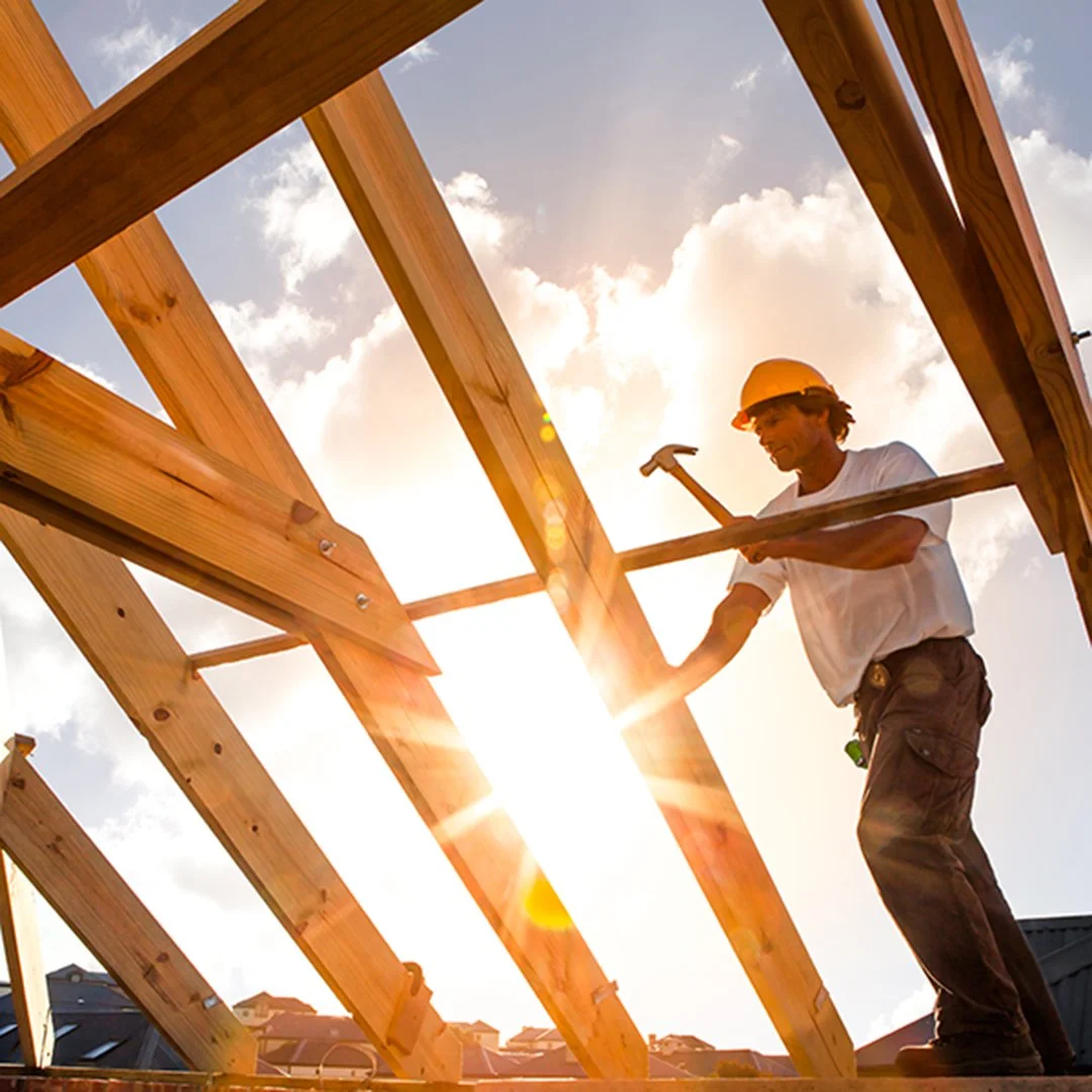 Image of construction work hammering on framework of home