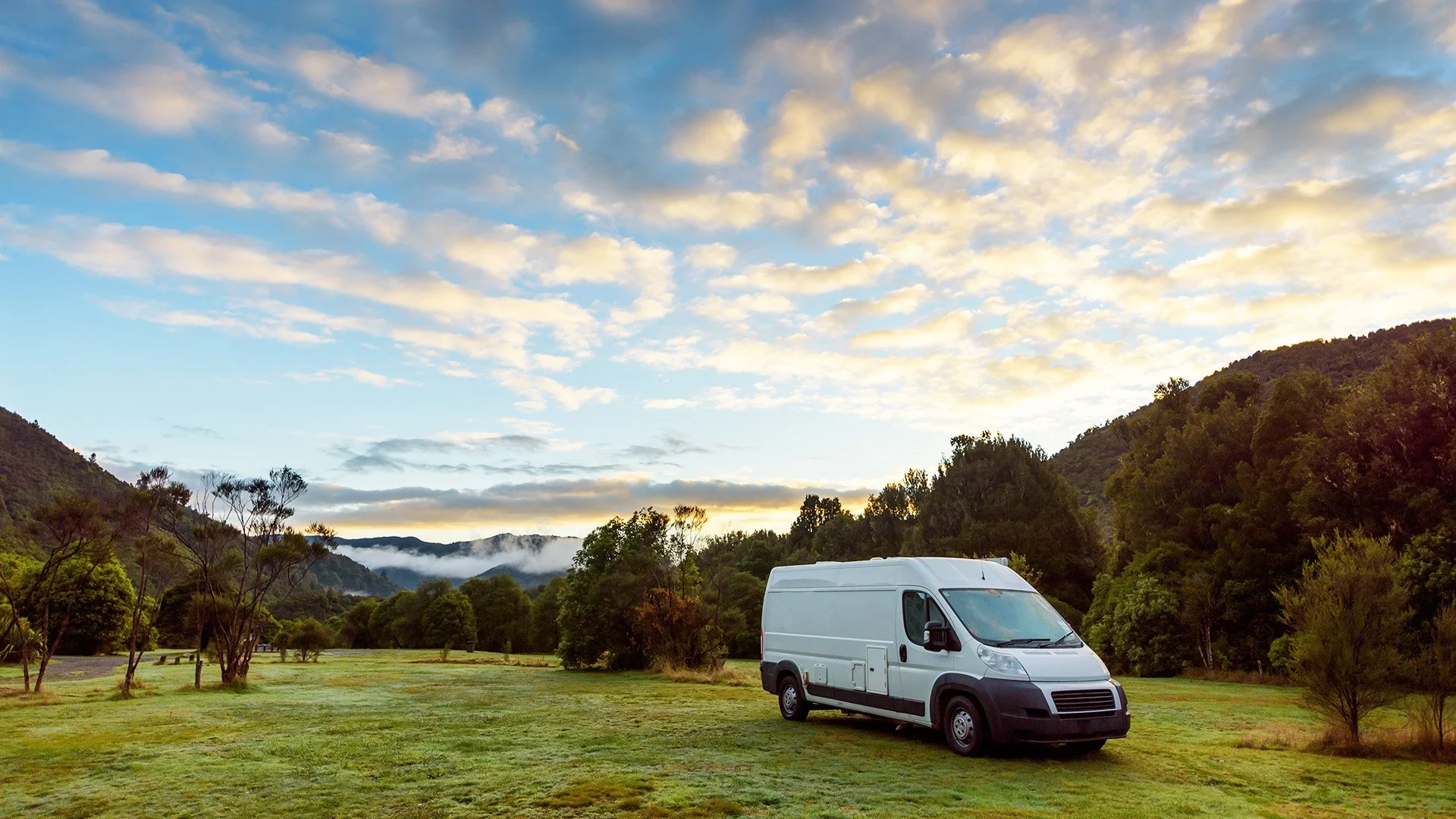 Image of camper van in outdoors with mountains in background.