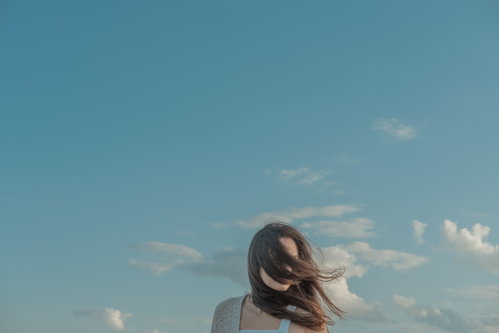 Person with long hair blowing in the wind against a sky backdrop