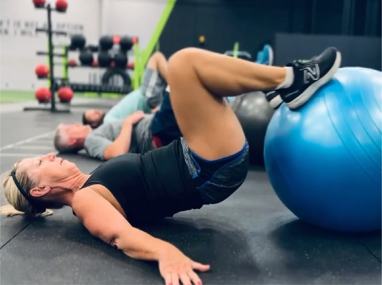 Mom performing stability ball hip thrust in small group training session