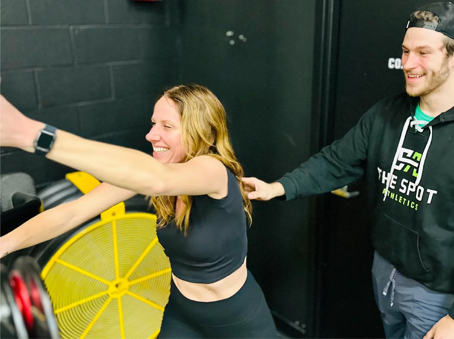 Mom doing sled push with trainer support at The Spot Athletics gym