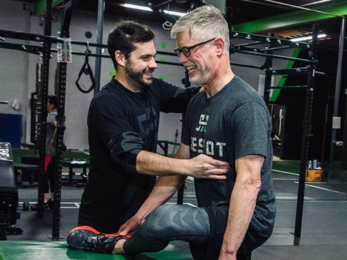 Coach working one-on-one with an older male client on form, technique, and mobility at The Spot Athletics