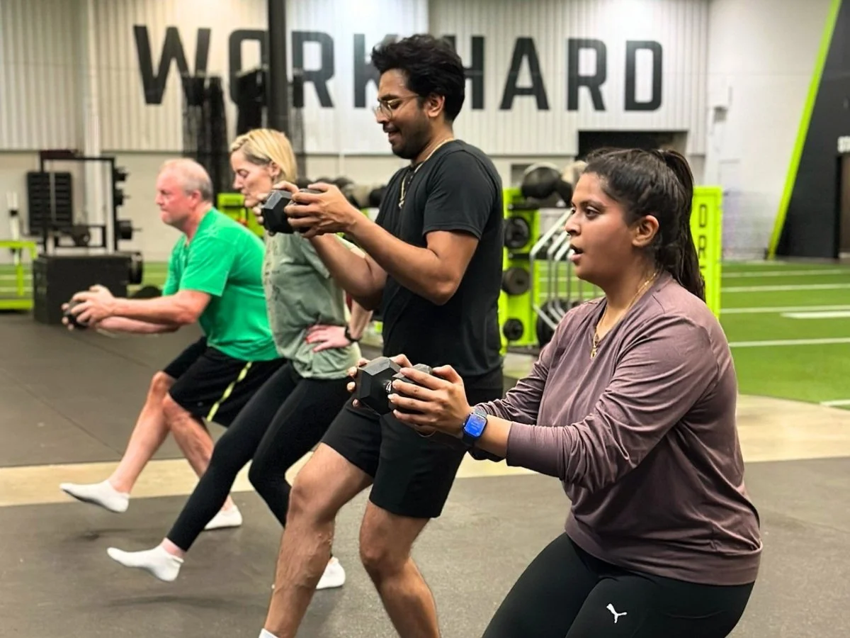 Small group fitness clients doing single-leg squats with weights at The Spot Athletics in Dublin, Ohio