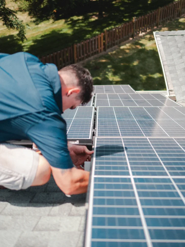 A person installing or maintaining solar panels on a house roof.