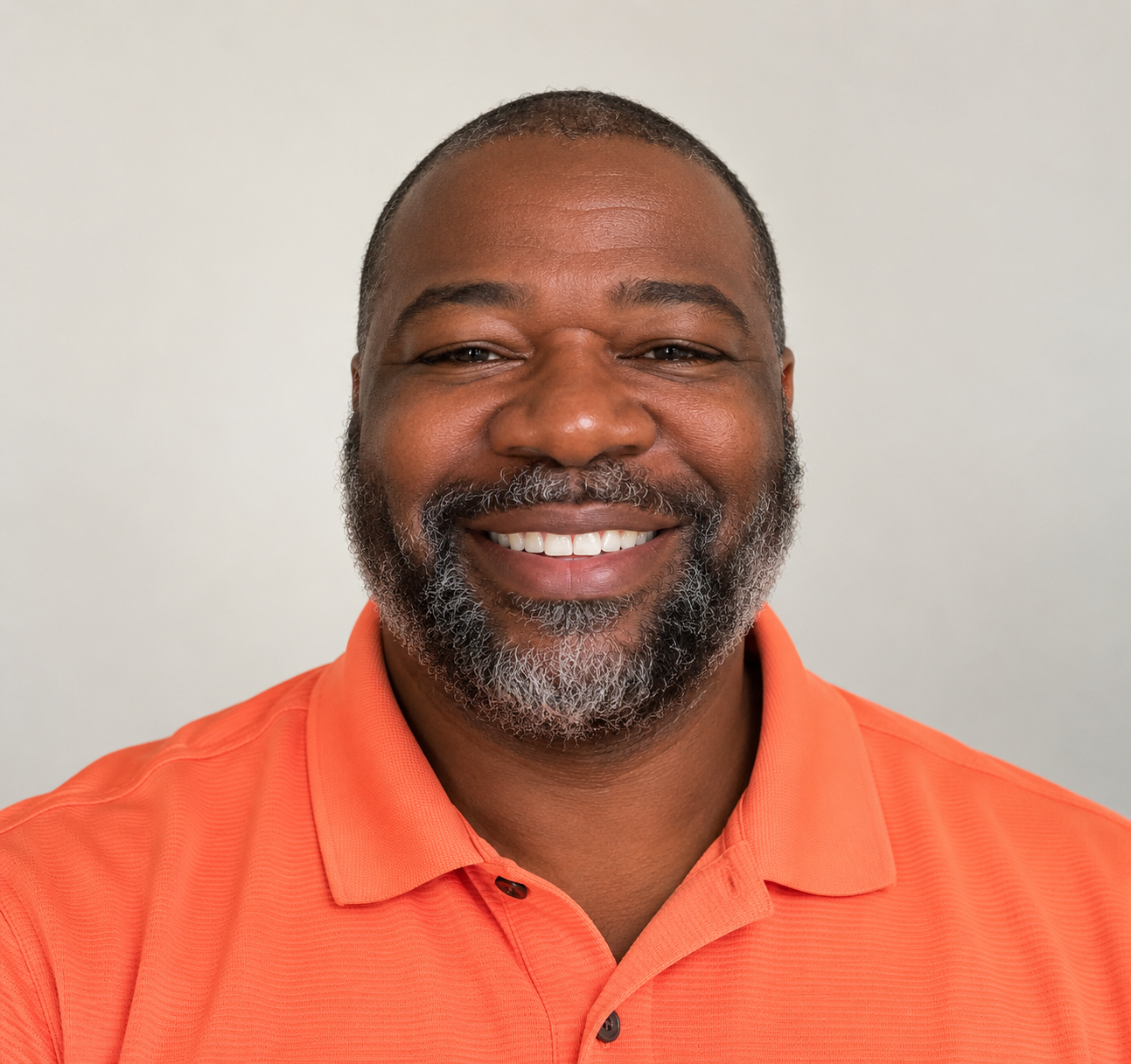 Alti Taylor smiling in an orange polo shirt.