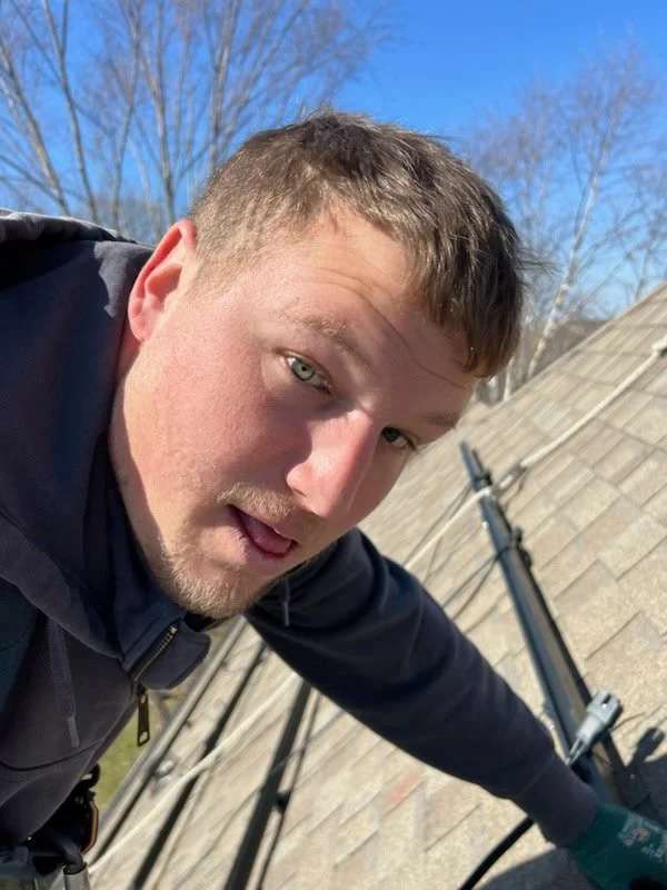 a man installing solar on a roof with a clear blue sky in the background