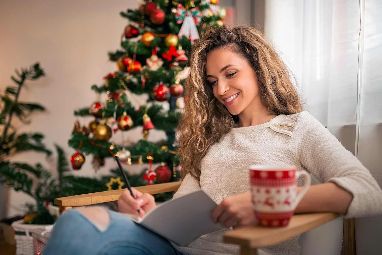 A woman sits comfortably with a cup of coffee, focused on IFS part mapping to help her navigate the holidays.