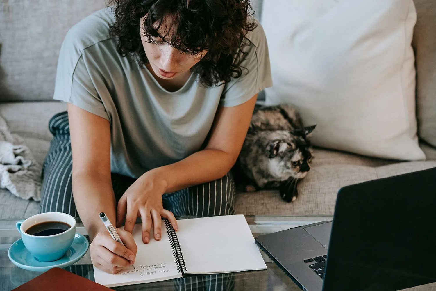 A woman writing down realistic and achievable habits for the New Year 2025