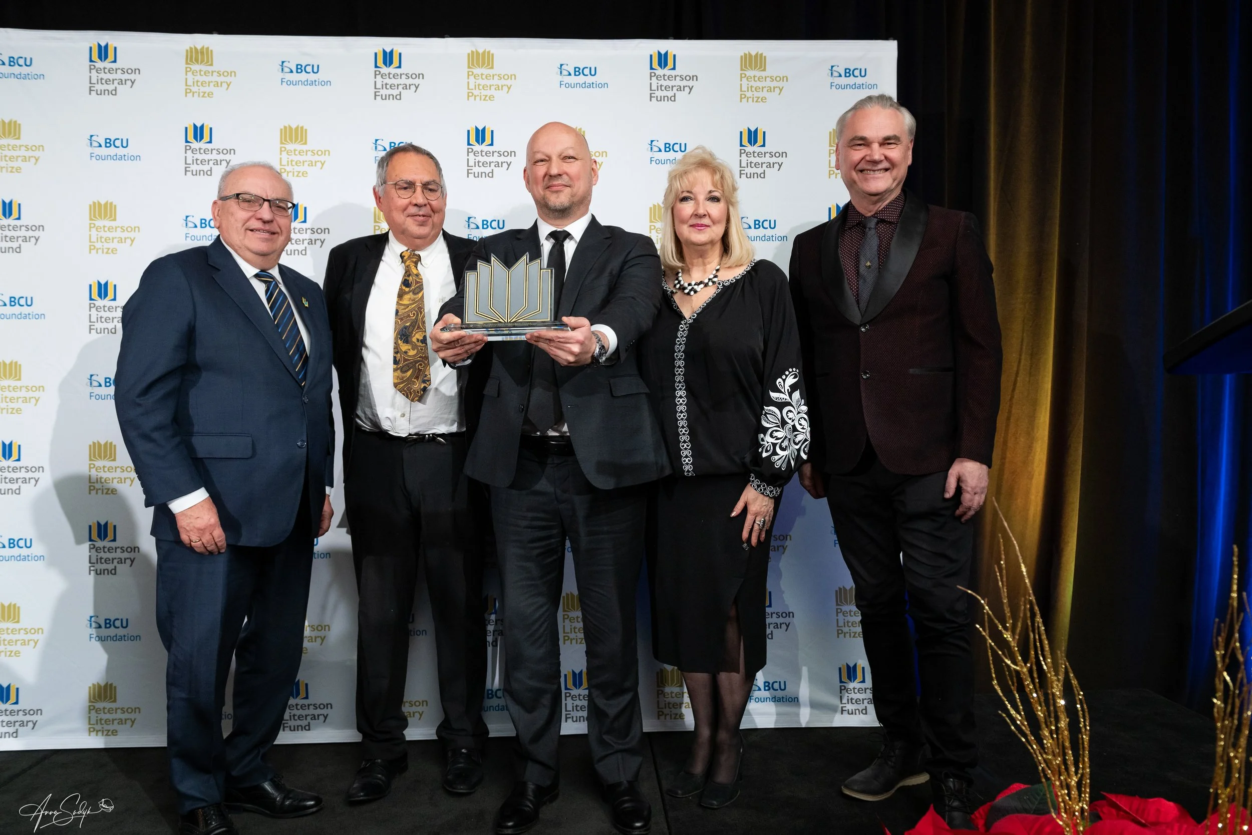   Yaroslav Trofimov (centre) holds the 2024 Peterson Literary Prize crystal award. To his right: jury chair Lisa Shymko and jury member Marko R. Stech. To his immediate left: jury member Askold Krushelnycky and BCU Foundation chair Bob Leshchyshen. (Photo credit: Anna Sudyk)  