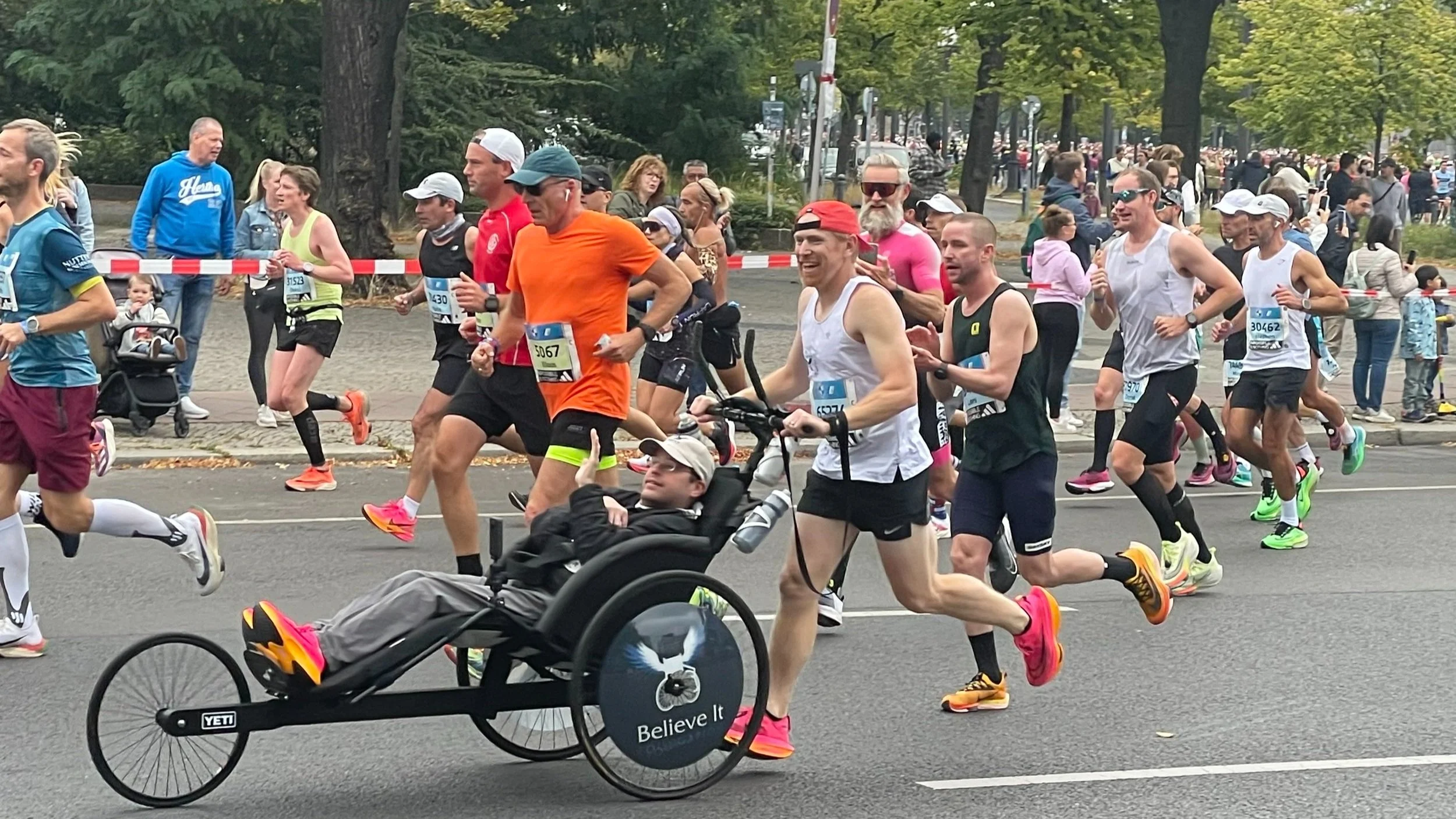 A runner pushes a participant in a racing wheelchair during a marathon..