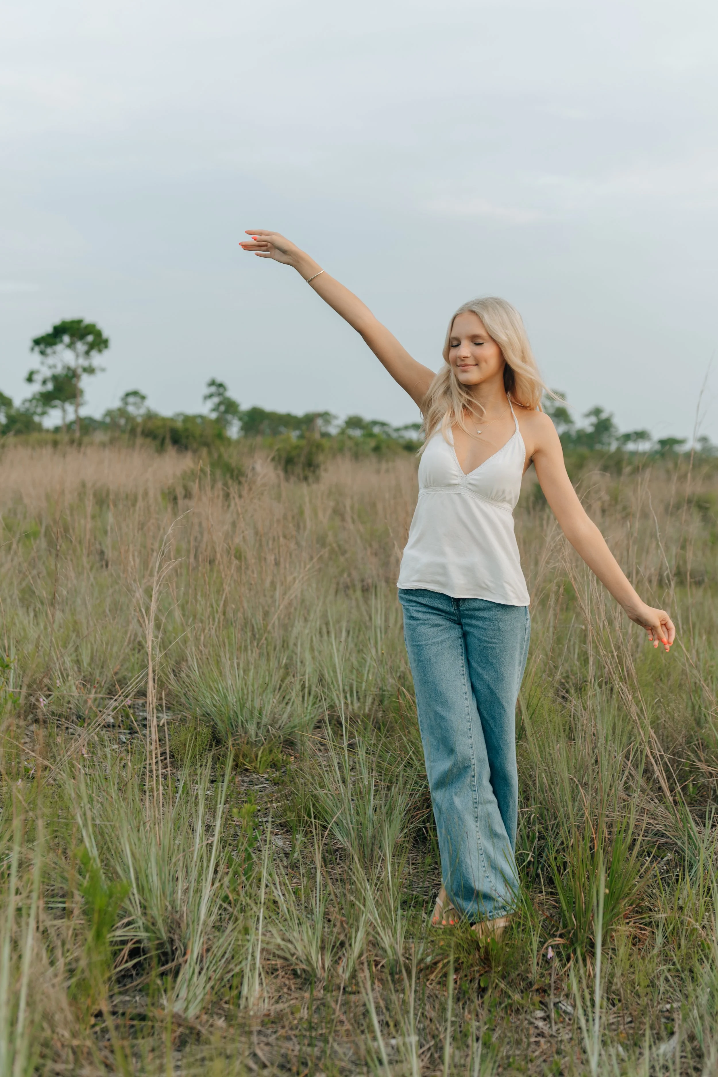 high school senior girl dancing in a tall grassy field in malabar florida