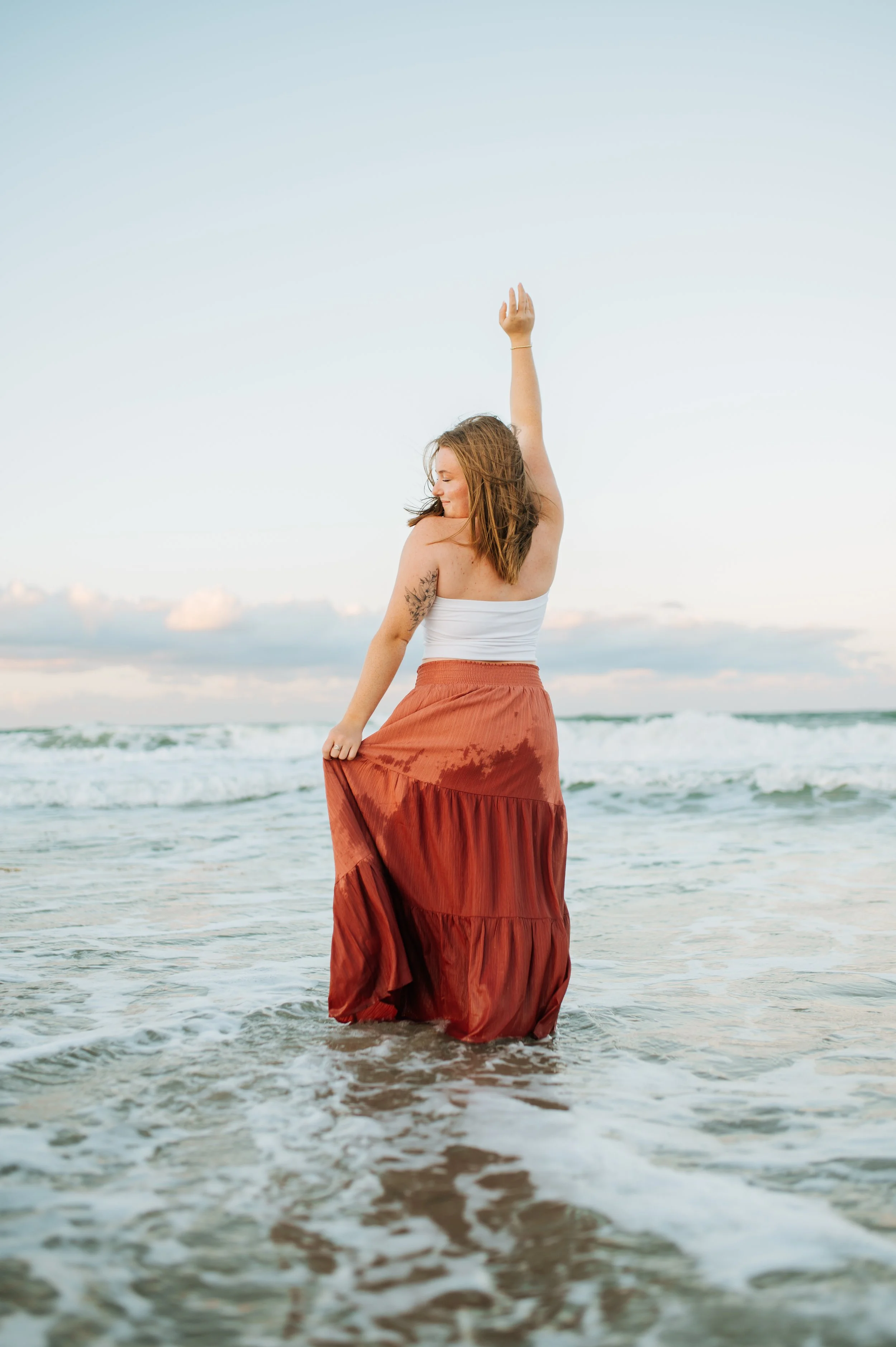 senior girl twirling around on the beach for her senior pictures