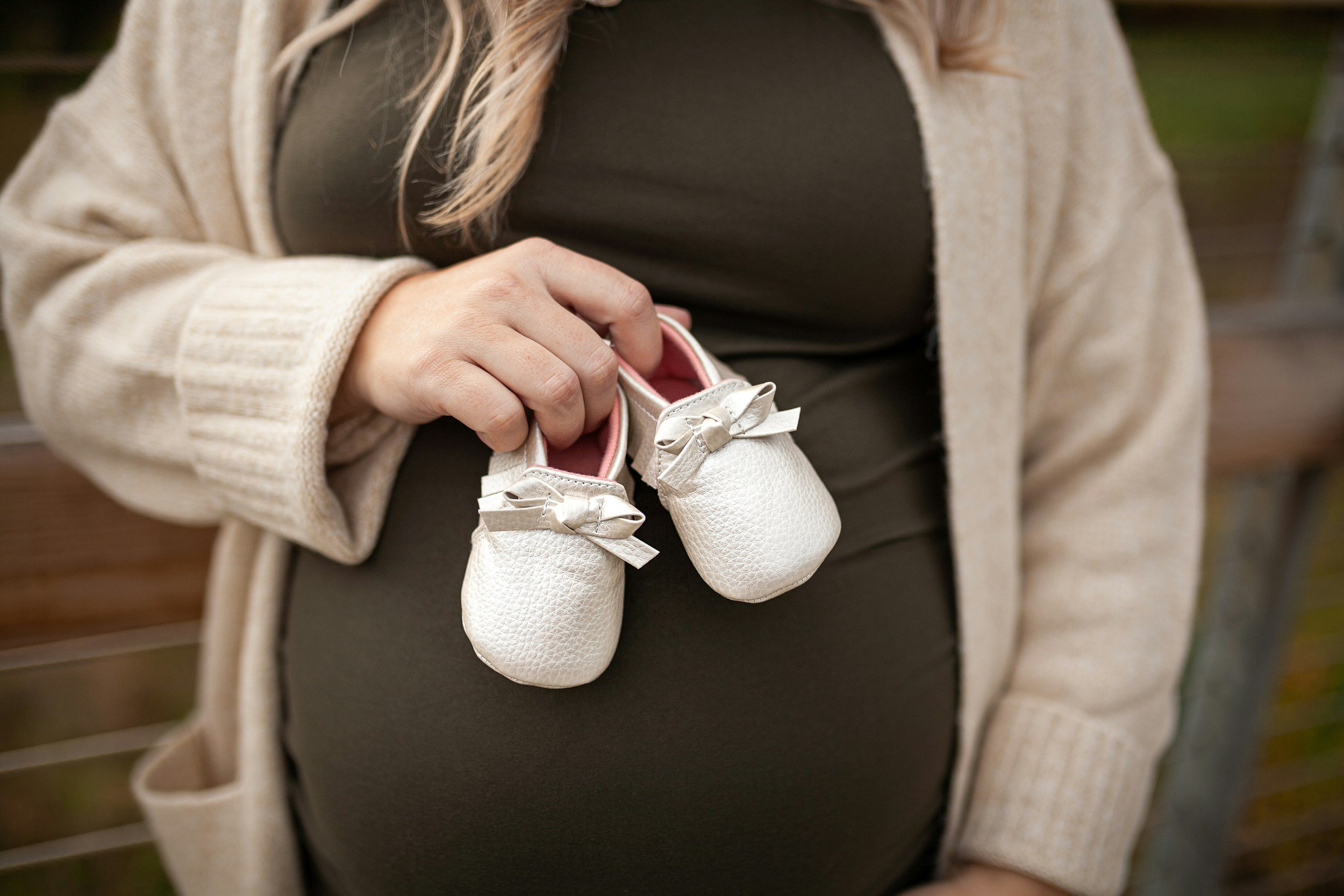 A pregnant mom hold two white shoes getting ready for her 3D/4D/5D (HD) Live Ultrasound session at Sweetface Scans Inc.