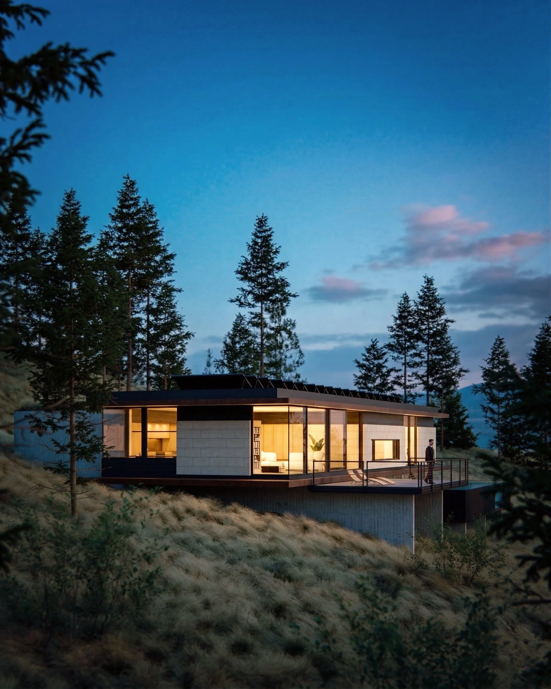 Long, low house on a forested hillside at dusk, with warm interior light visible through broad glazing.