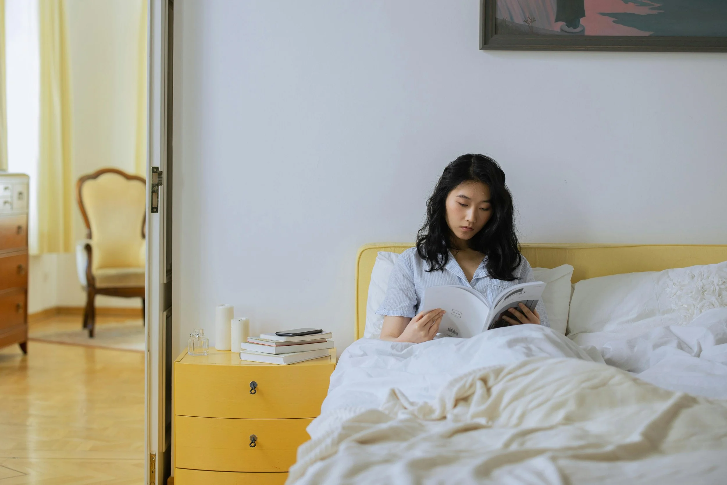 Person reading a book in bed as part of a calming bedtime routine to improve sleep