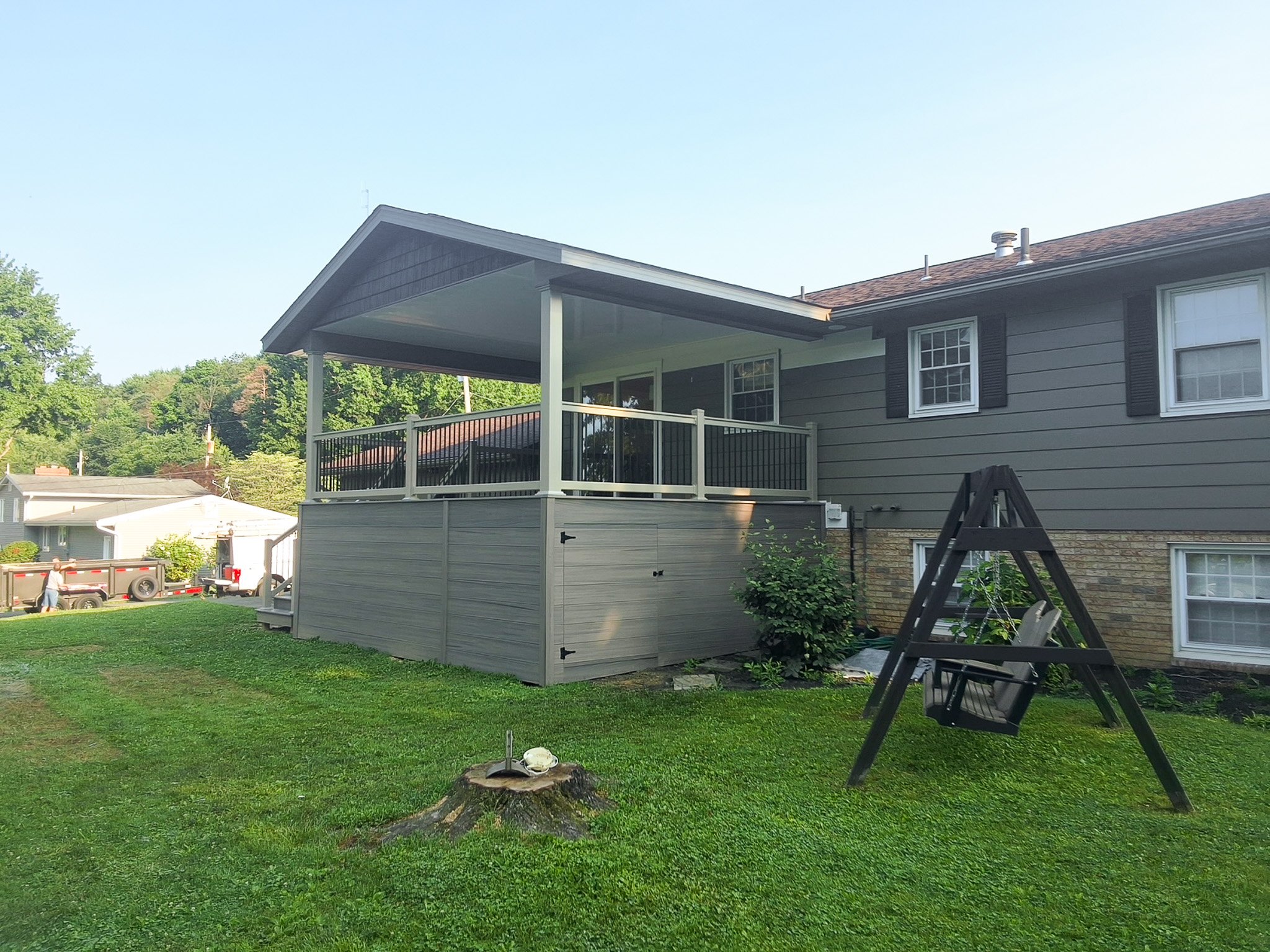 Backyard porch with a gable roof, railing, and staircase.