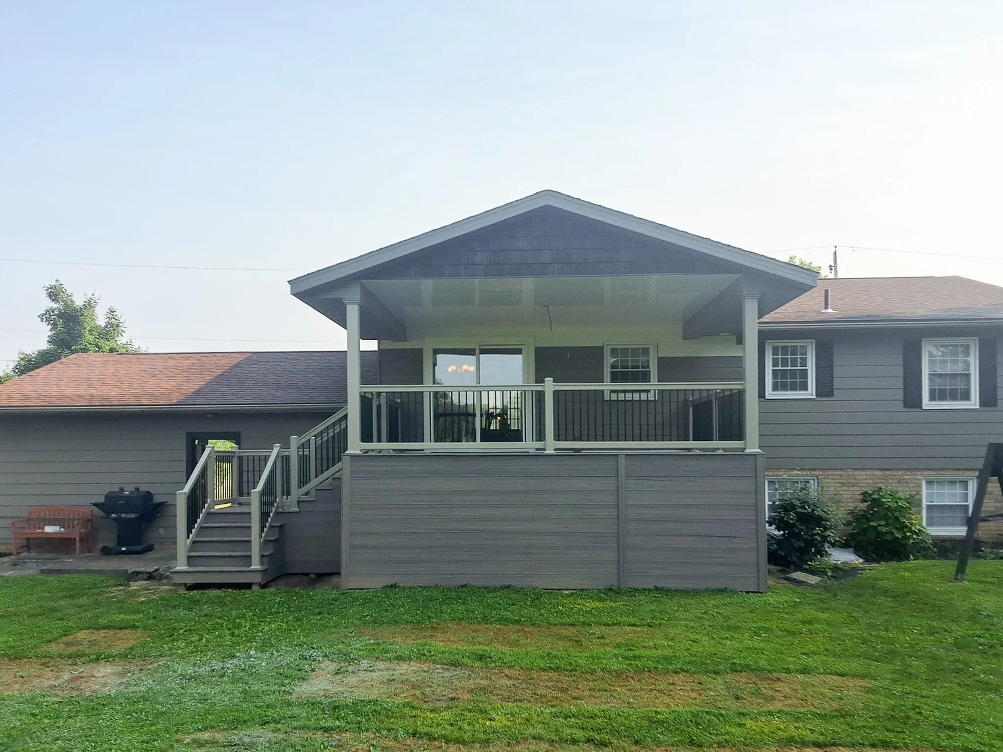 Backyard porch with a gable roof, railing, and staircase.