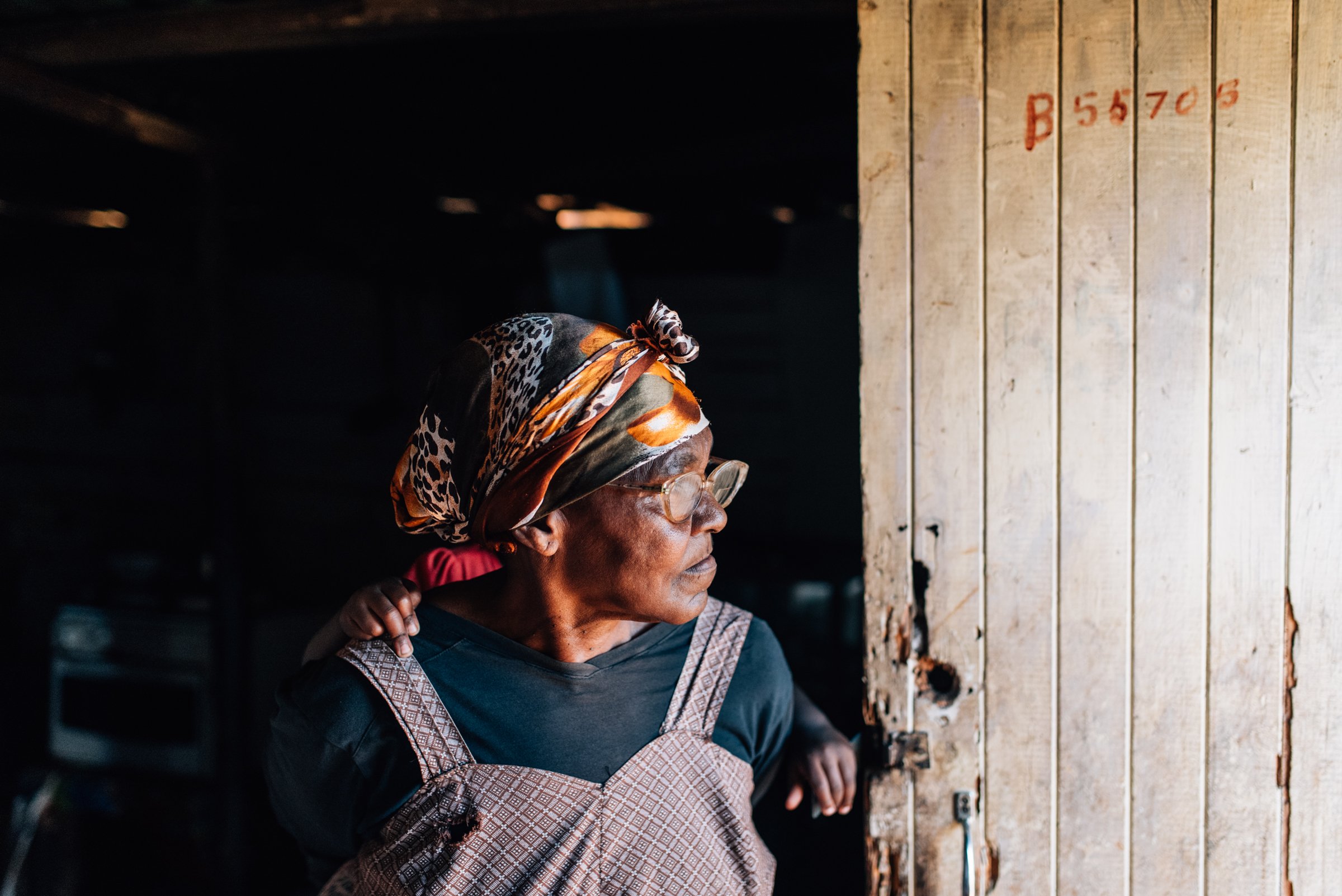 Woman gazes from her home in an informal settlement - South Africa.jpg