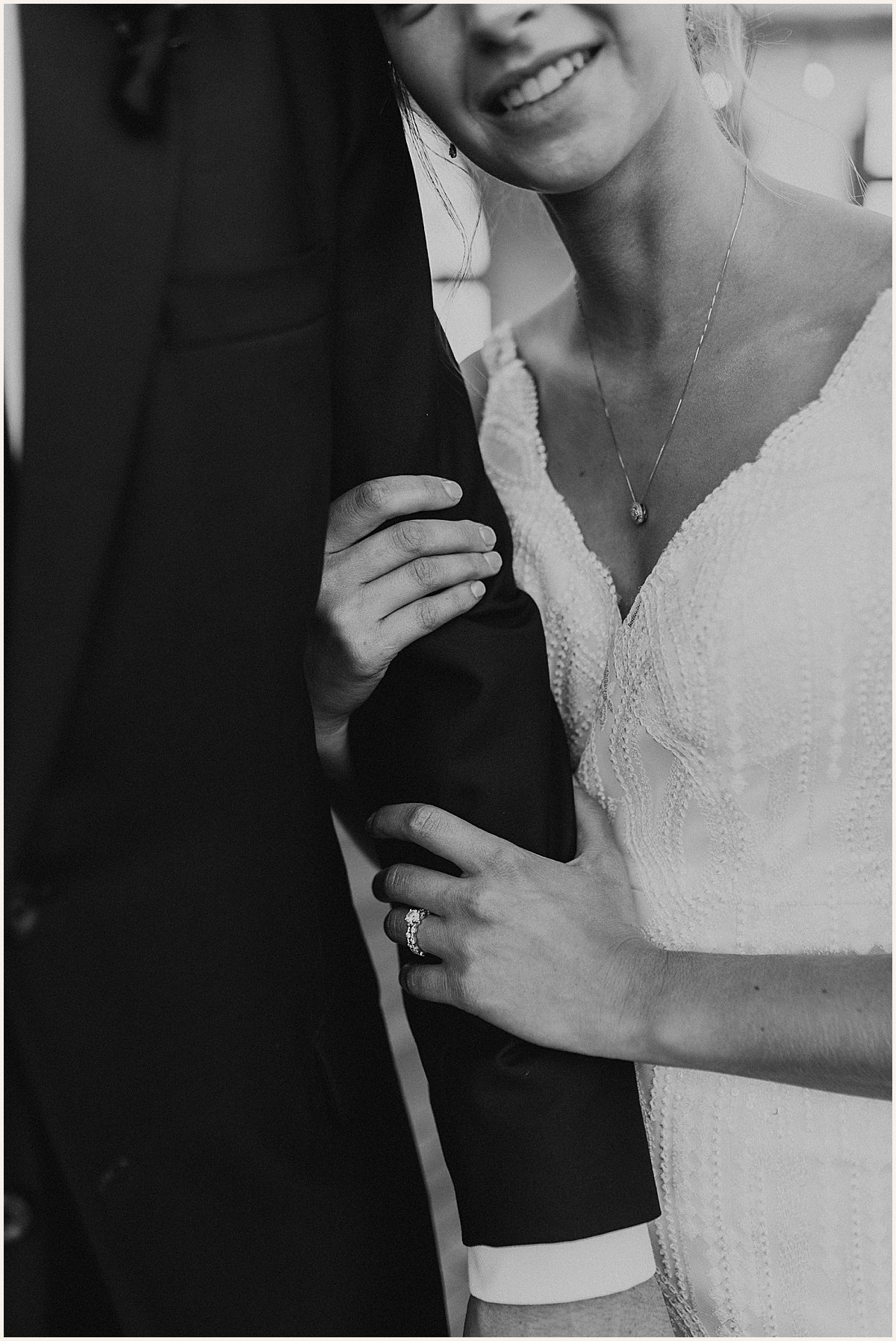 Black and white image of bride holding grooms arm and showing of wedding rings | Lauren Parr Photo