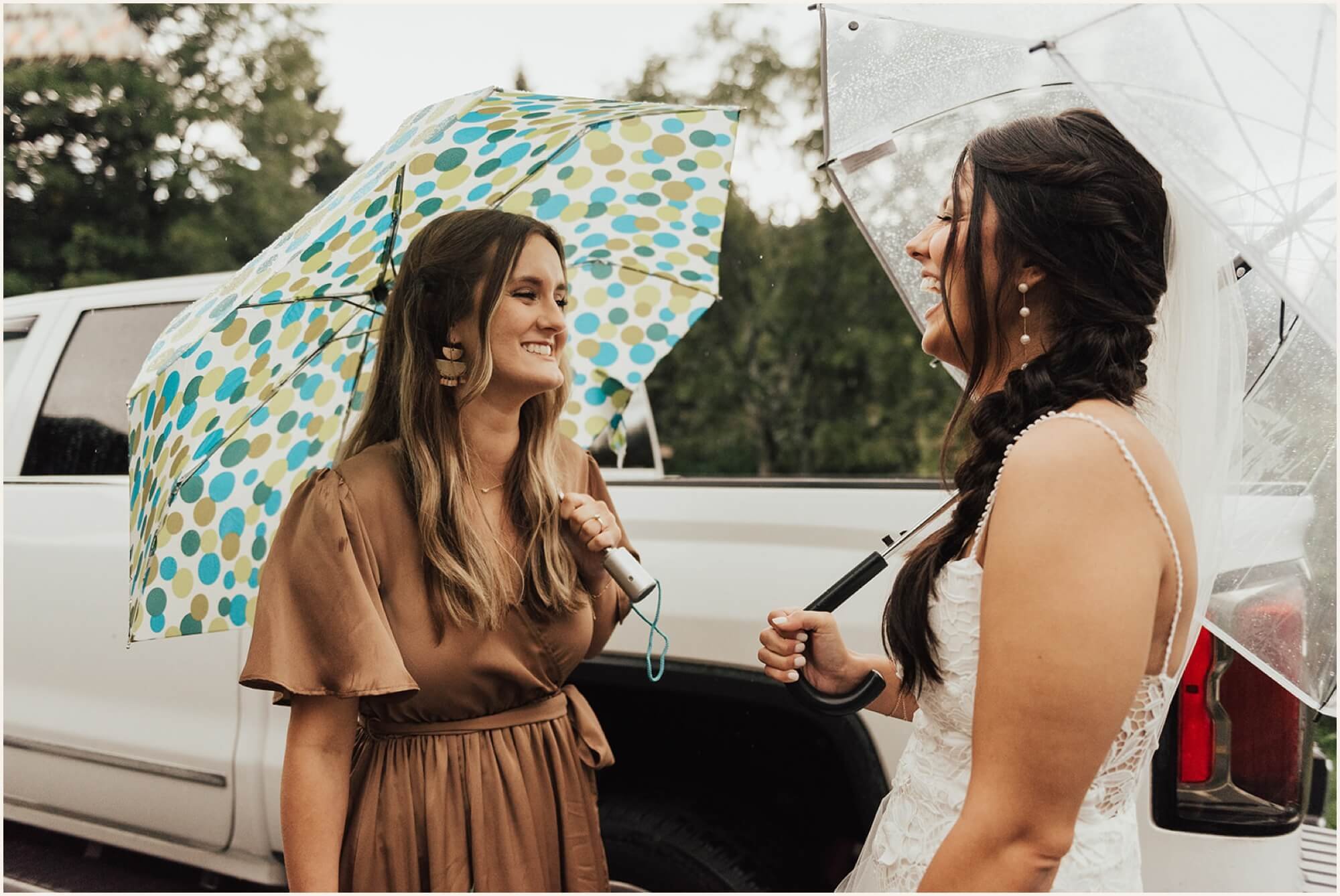 Bride and bridesmaids holding umbrellas and talking