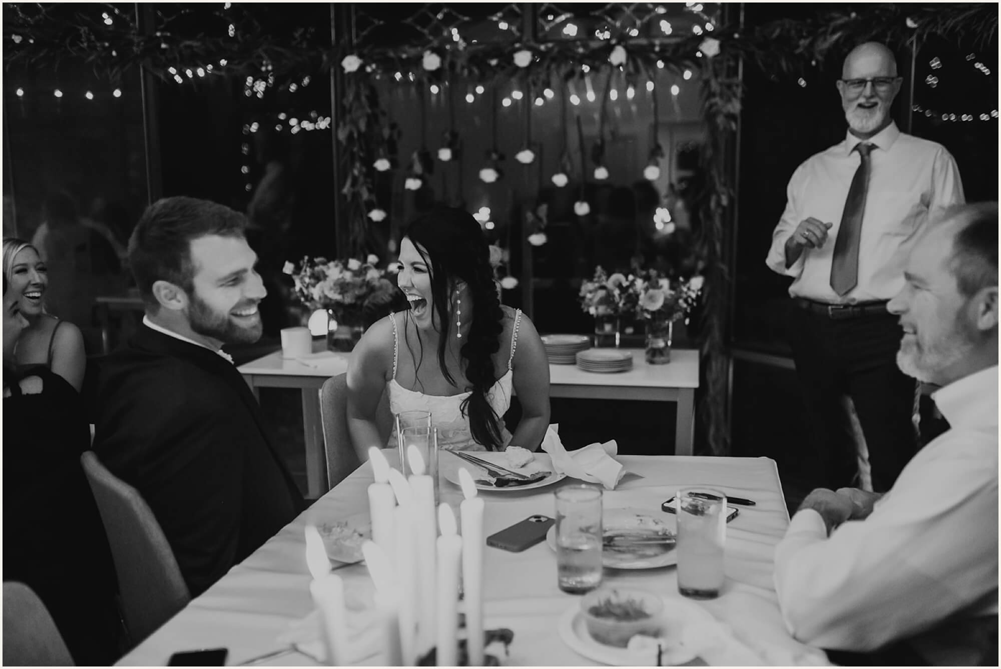 Bride and groom laughing during reception toast