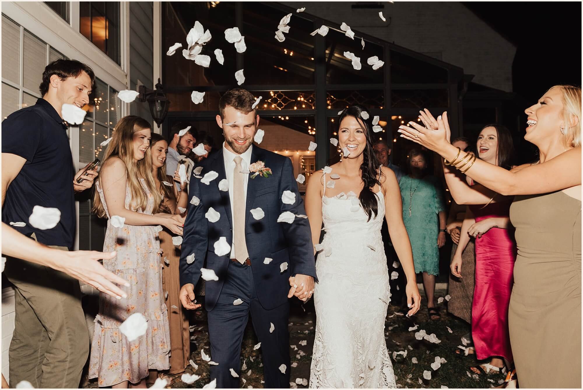 Bride and groom exiting reception with rose petals