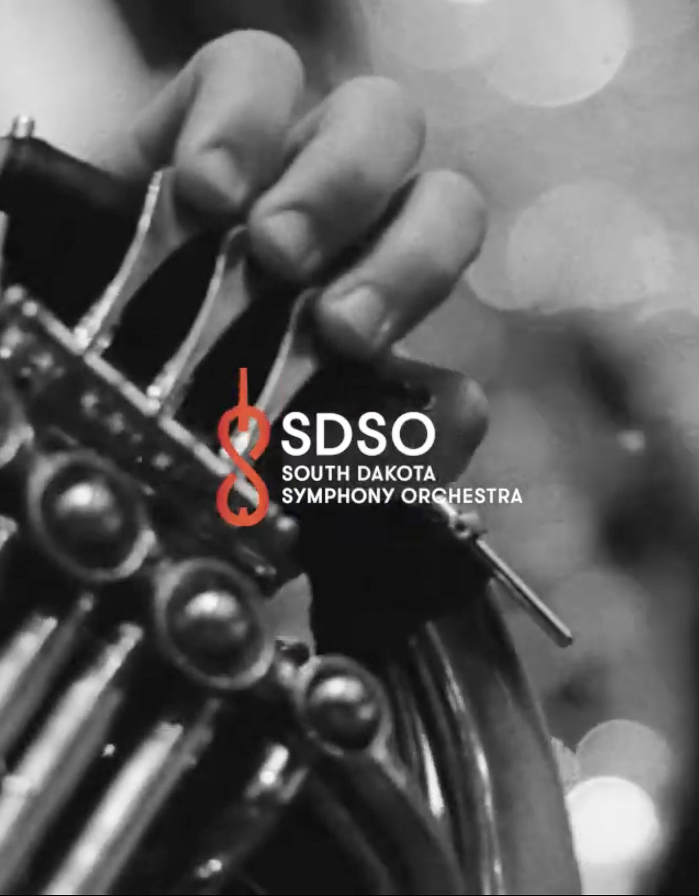 Close-up of a hand playing a musical instrument, with the logo and text for the South Dakota Symphony Orchestra overlayed.