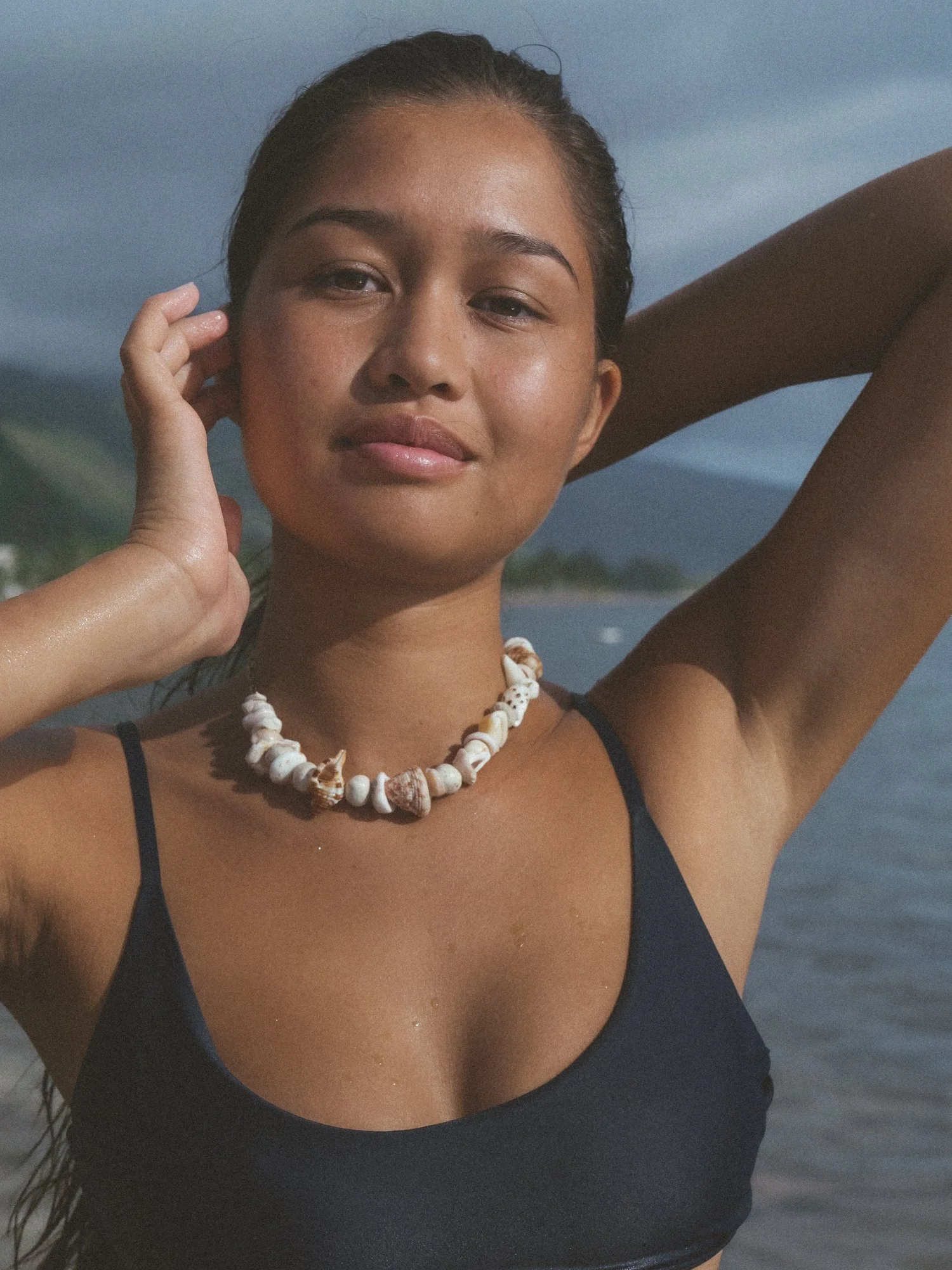 Closeup photo of a model wearing a navy bikini and Studio Dixie Shell Choker Necklace in Tahiti, French Polynesia for a fashion and brand photoshoot with photographer, Lynsey Garfinkel 