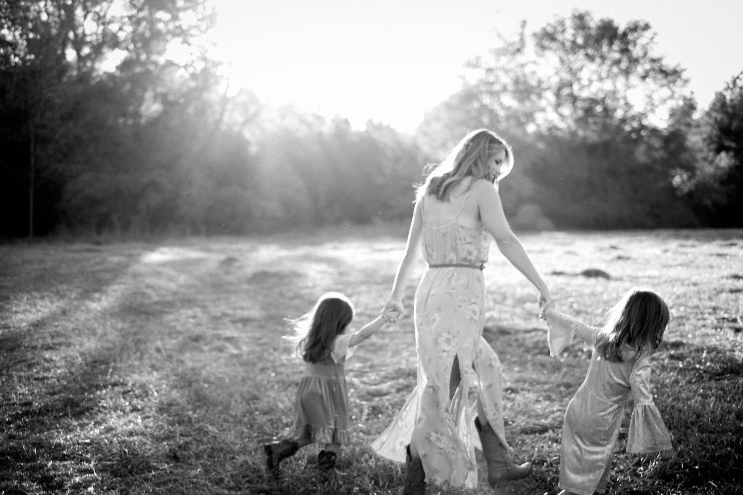 black and white photo of mother and daughters walking through field