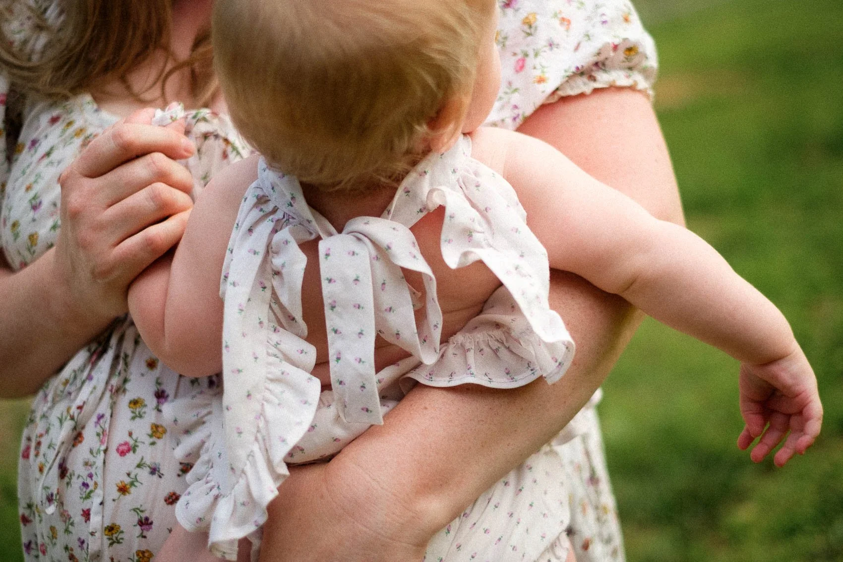Details of mom and baby's patterned dresses, mom holding baby's hand