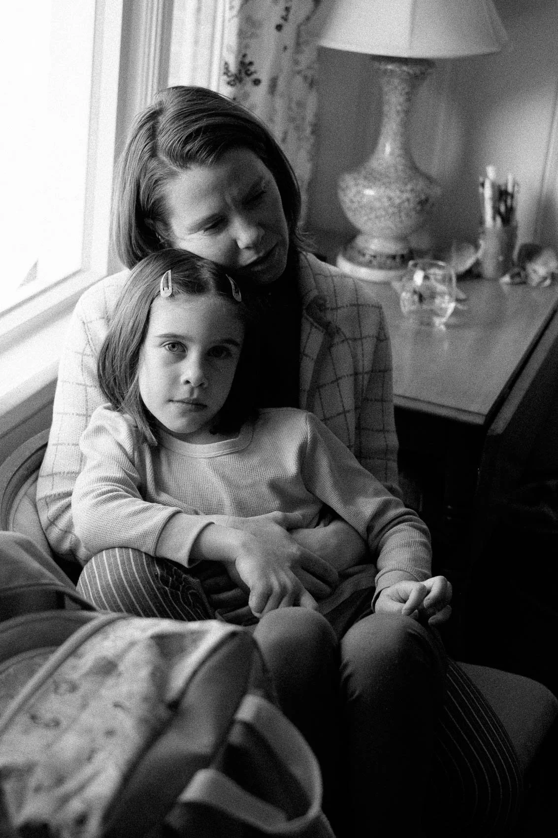 Black and white photo of mother and daughter sitting by a window