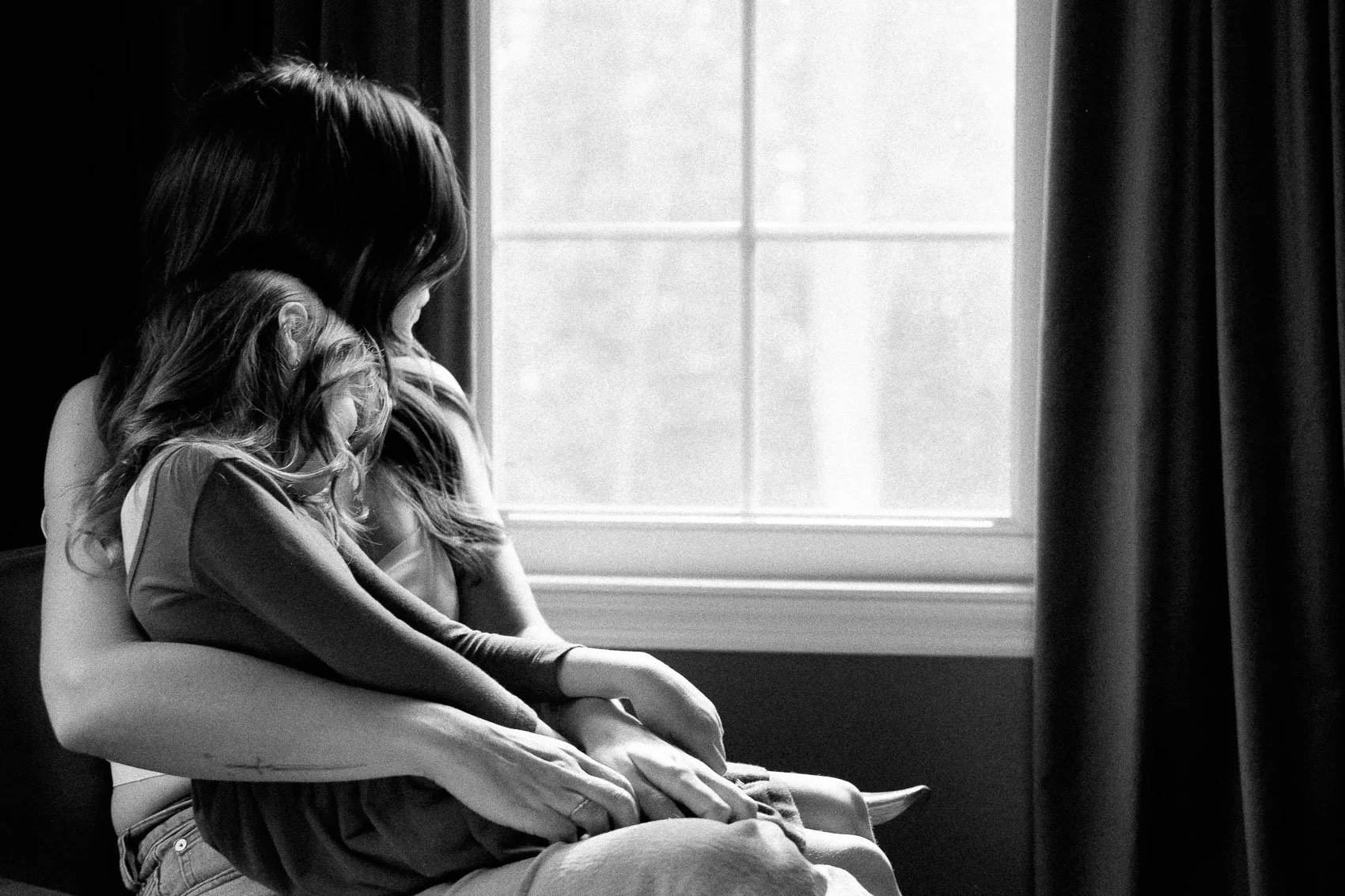 Mom and daughter sitting in window light in black and white
