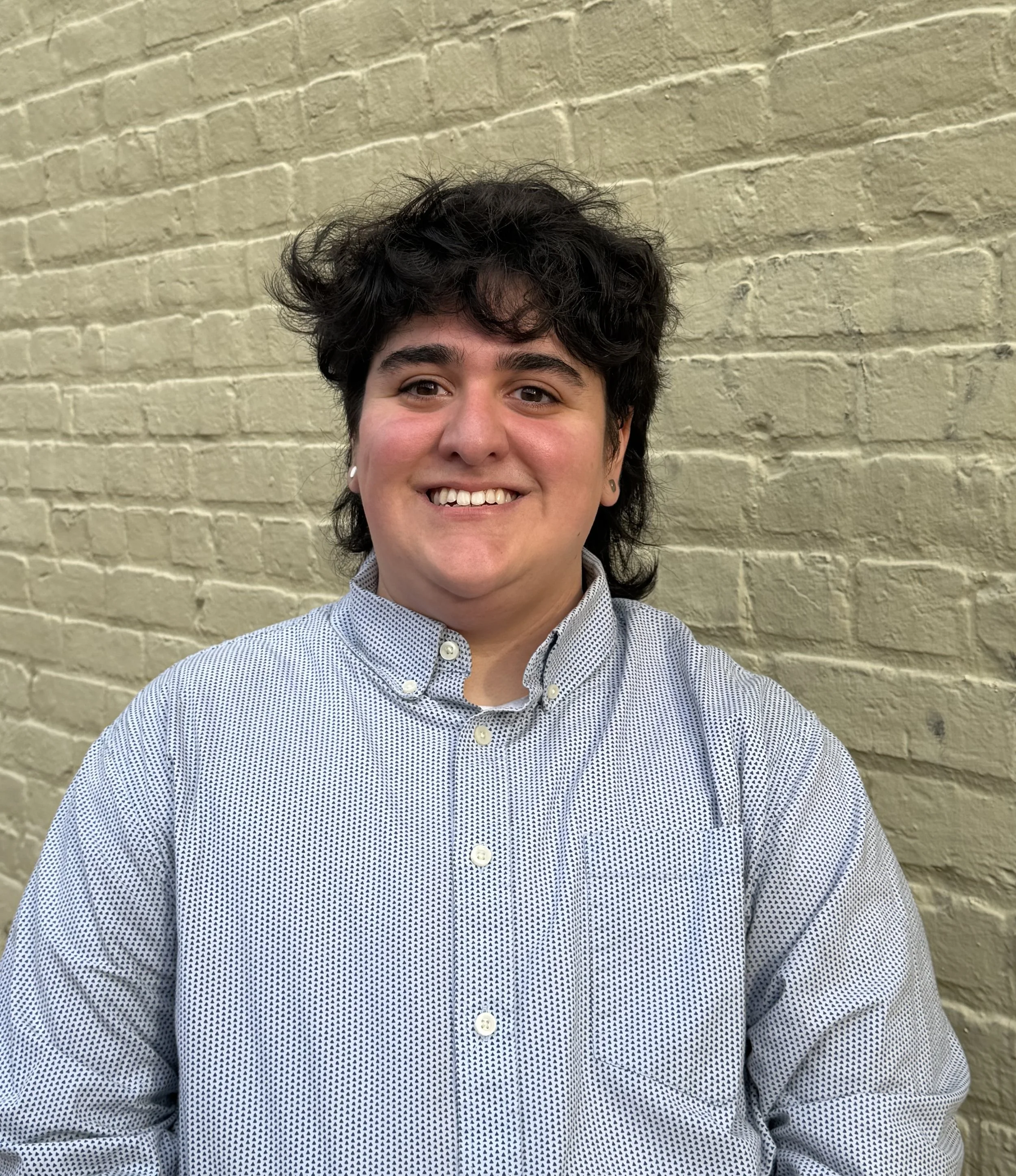 A Queer therapist in VA & DC  who is gender affirming smiling in a black shirt