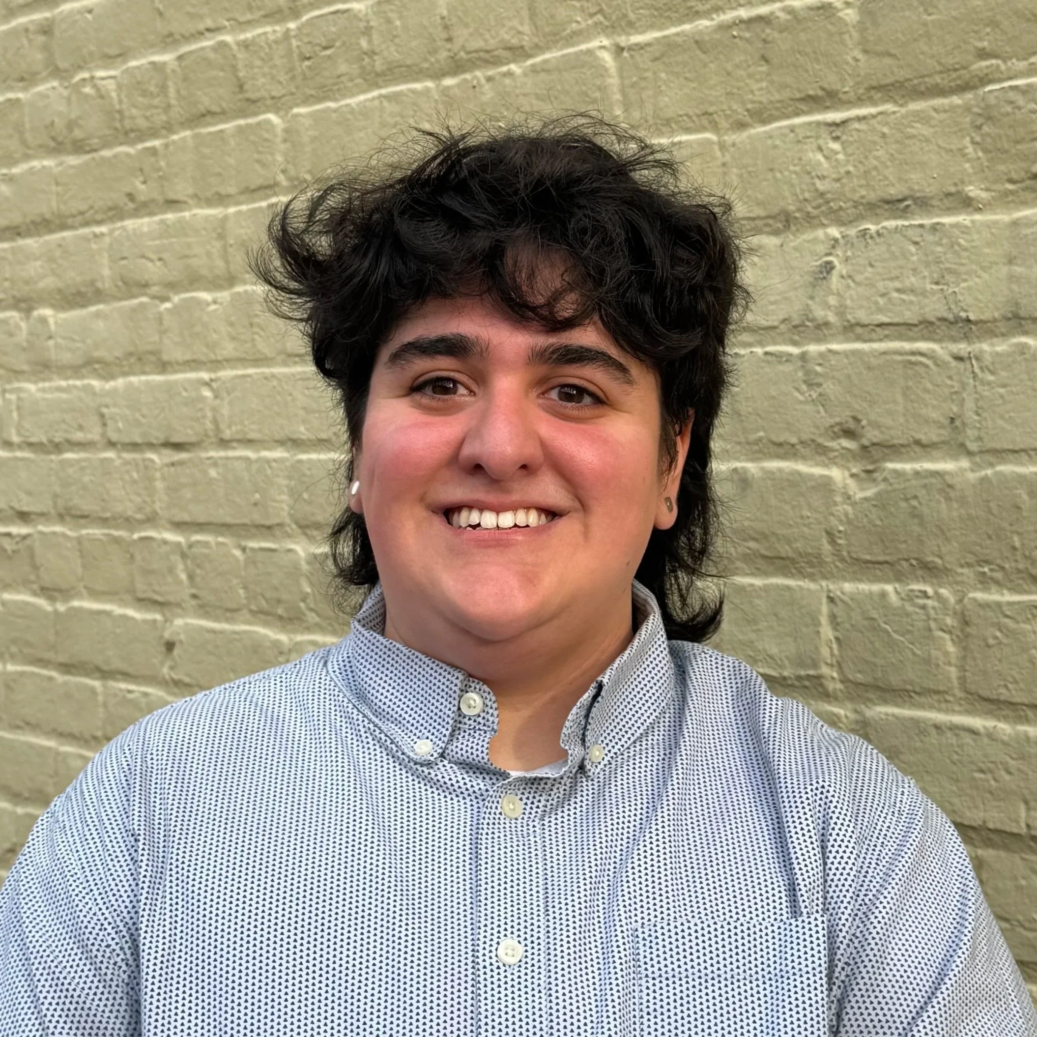 A Queer therapist in VA & DC  who is gender affirming smiling in a black shirt