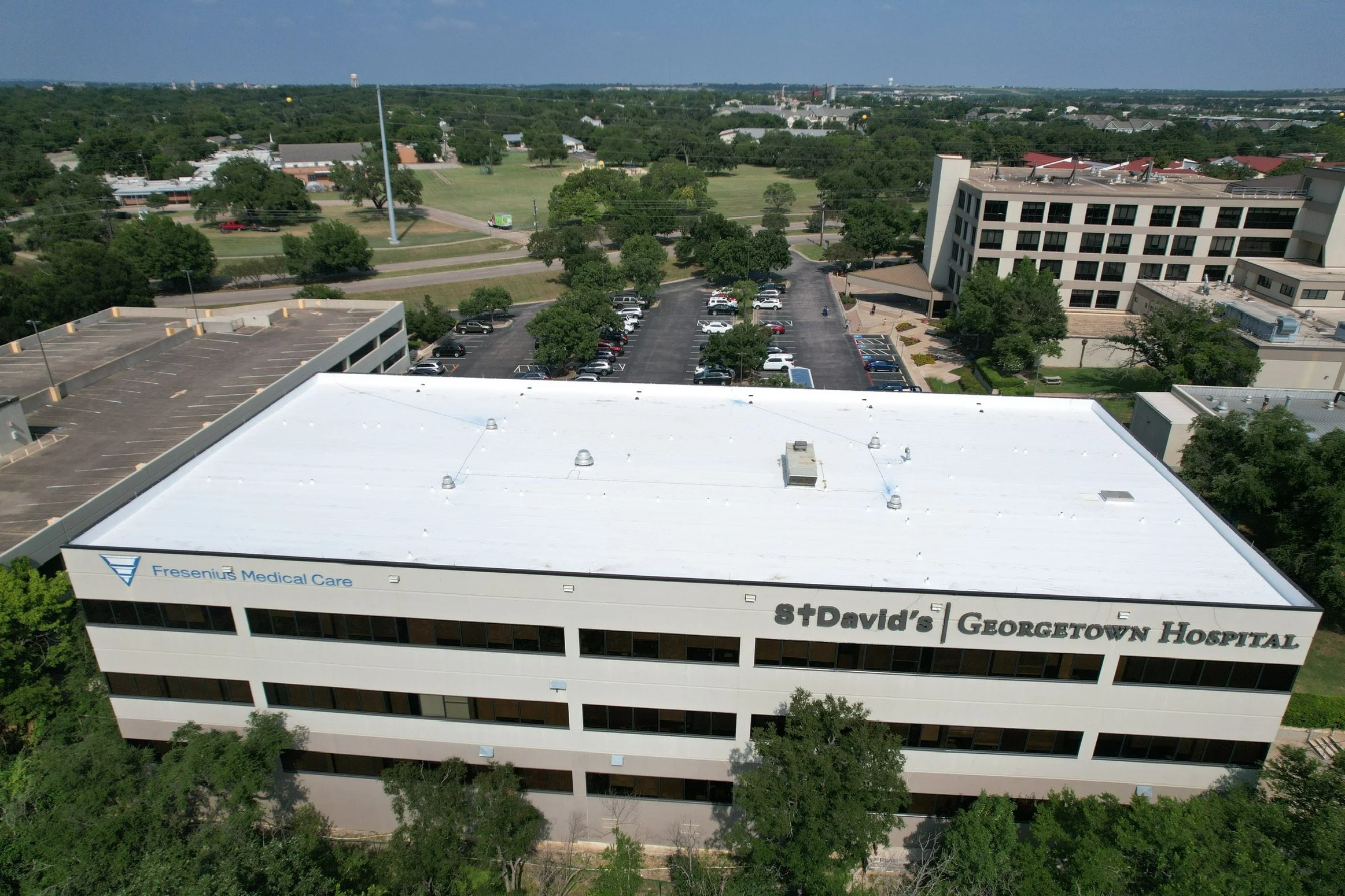 Aerial view of Georgetown Hospital and St. David's Medical Care building in a with parking lots and green trees.