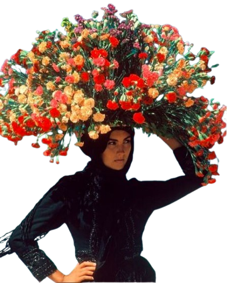 A woman dressed in black with a large floral hat made of colorful flowers.
