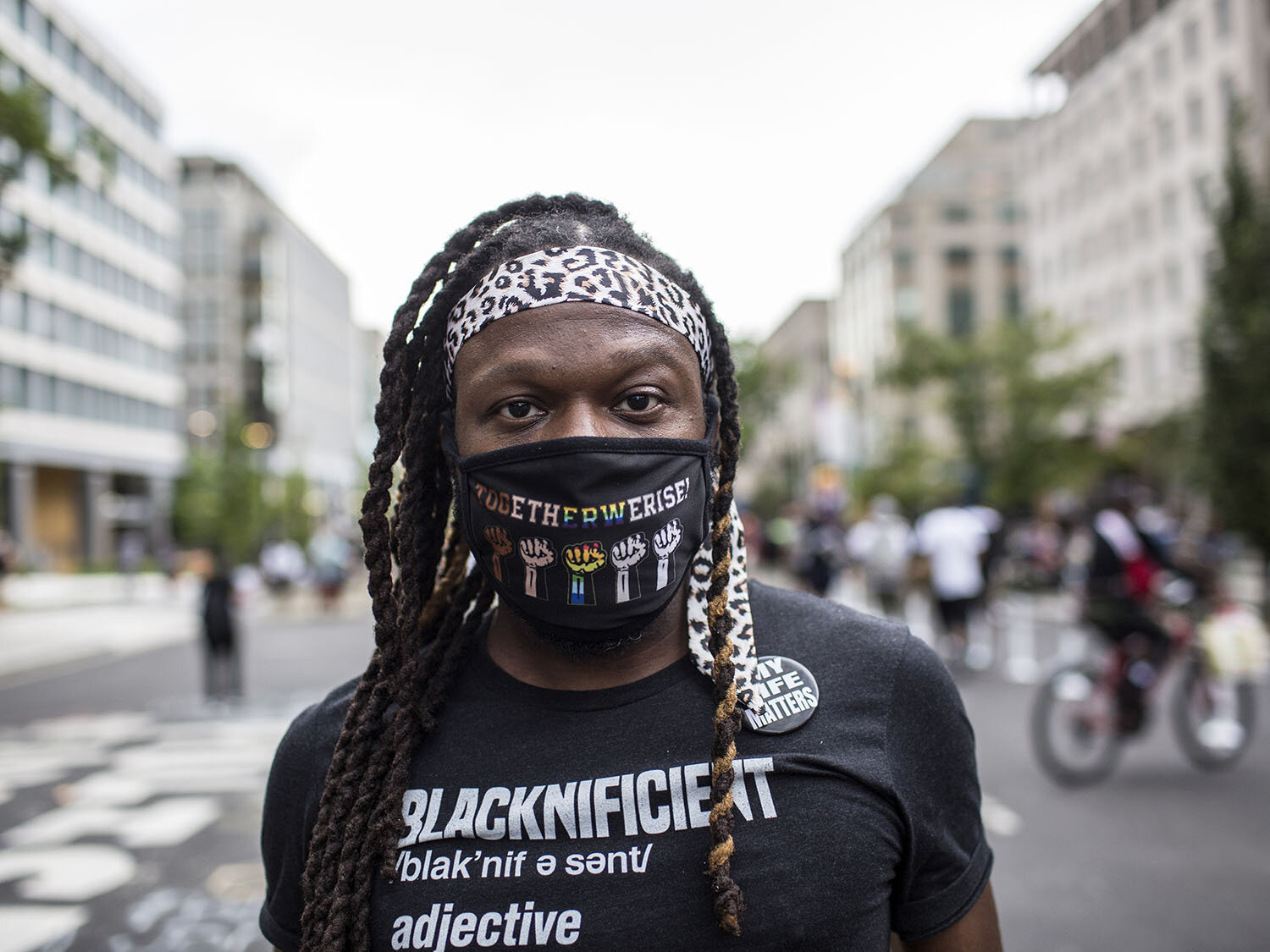  Name:  JeanMichael Prindilus   Age: 38  Date and Place the photo was taken: August 28, 2020, Black Lives Matter Plaza, Washington DC   His statement:  "My shirt describes me; I am Blacknificient, (adjective) one impressively dripping in black beauty