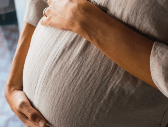 Pregnant woman gently holding her belly.