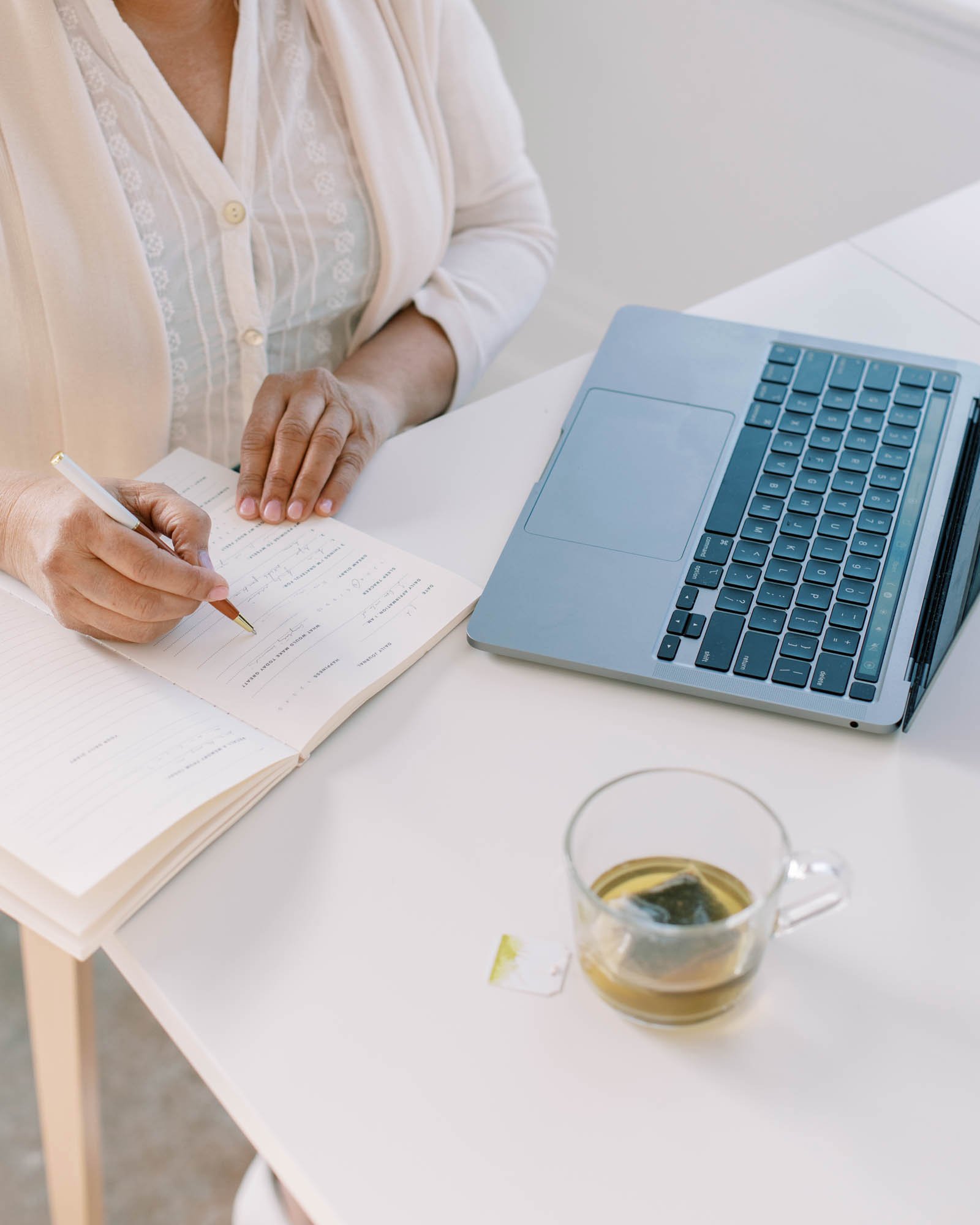 Woman planning her nutrition business marketing strategy in a notebook beside a laptop