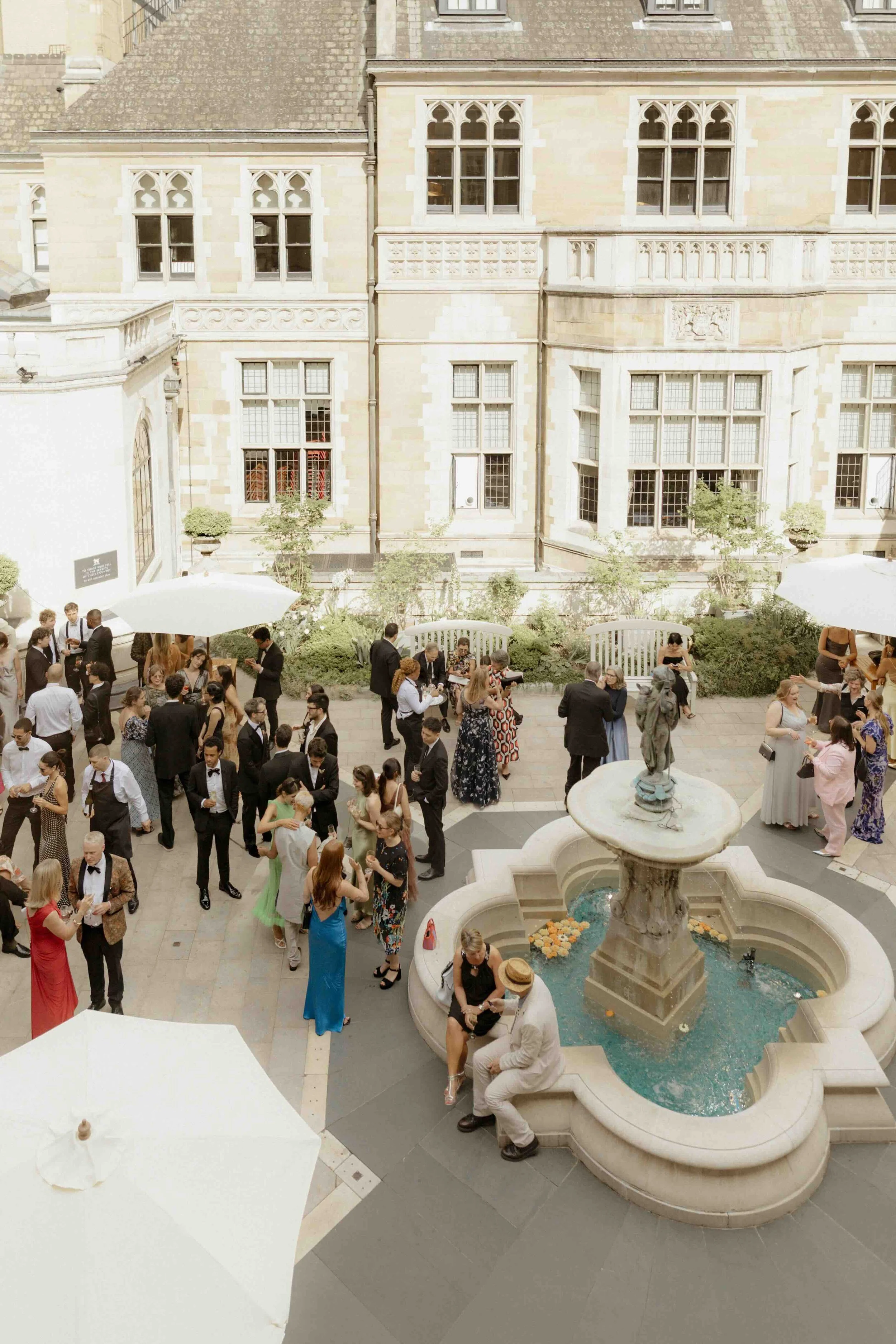 Guests mingle at fountain in courtyard of Merchant Taylor's Hall, London, for elegant summer wedding