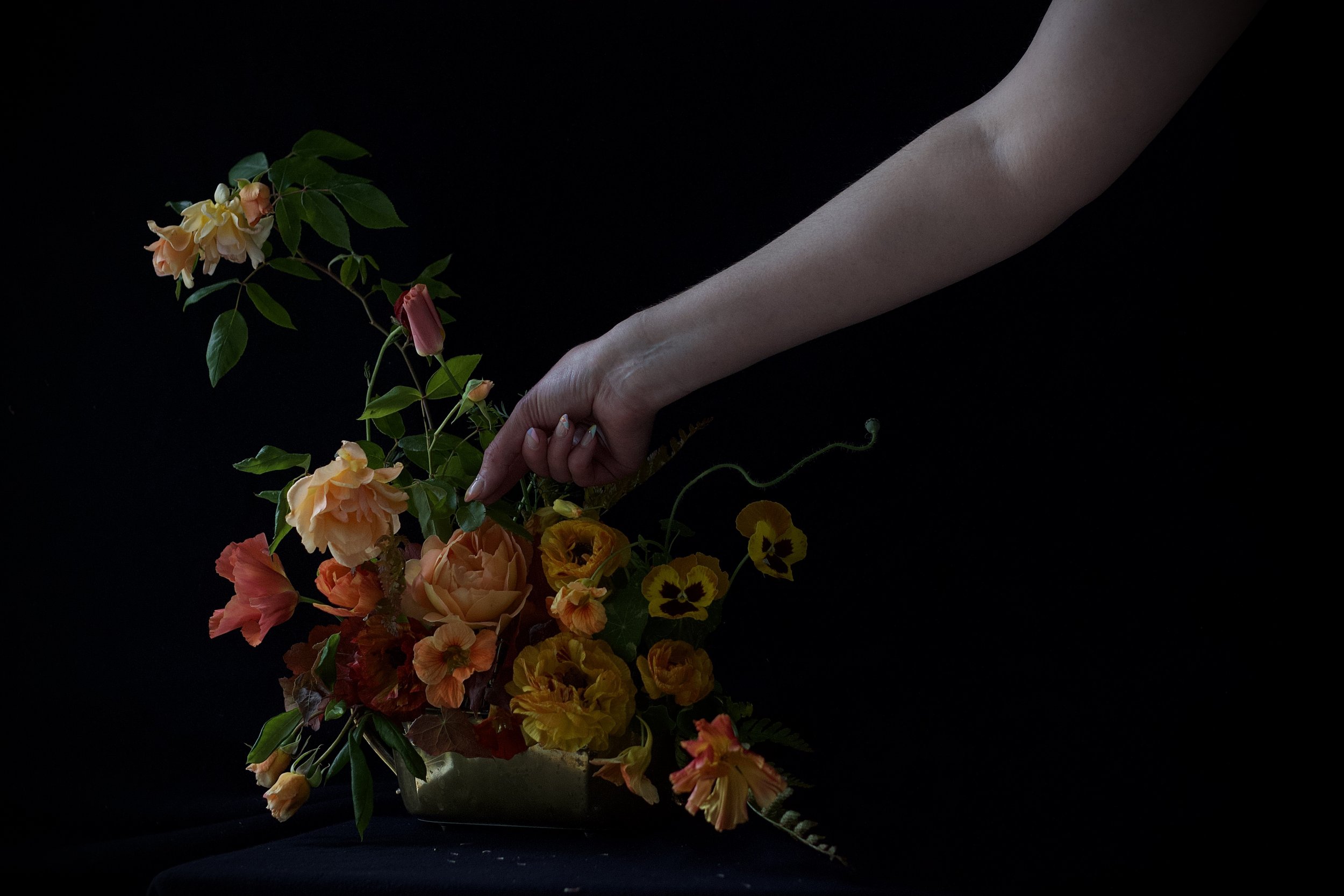 posed photograph of flowers with model in the dark pansies roses nasturtium summer design in vessel for event wedding soiree