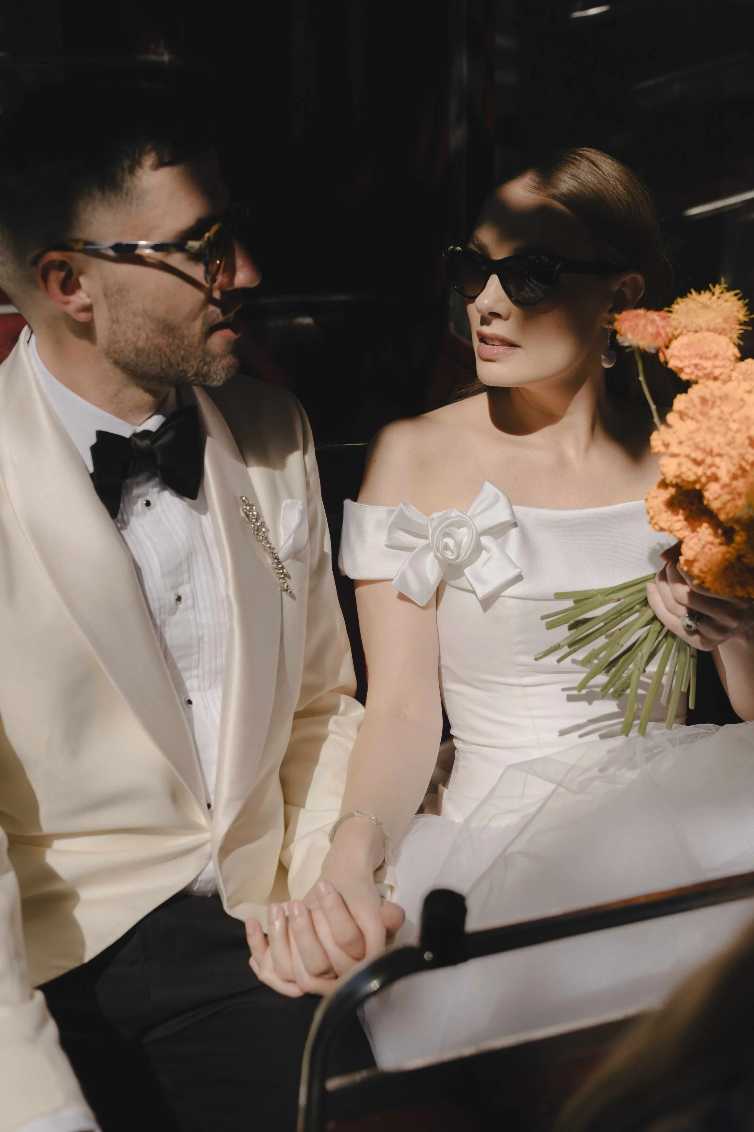 New York couple in London bus after ceremony with orange bouquet