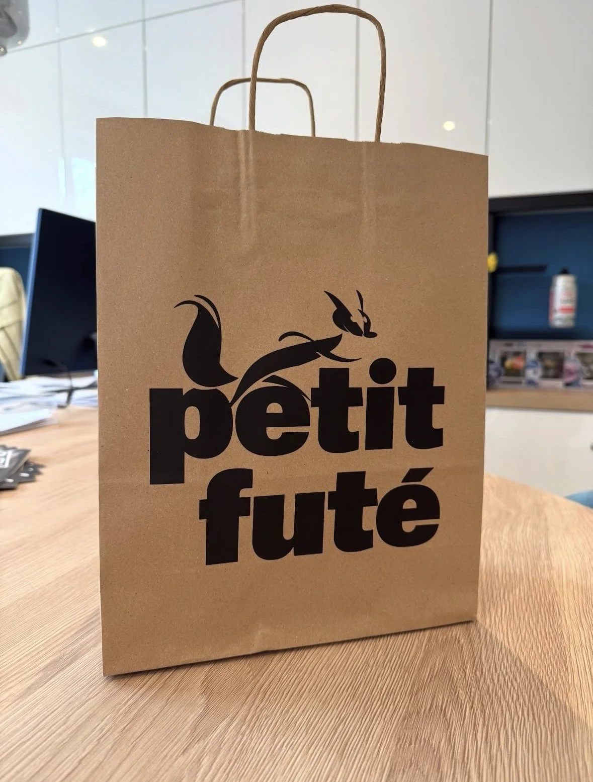 Sac en papier marron avec un logo noir représentant un renard stylisé et le texte "petit futé".