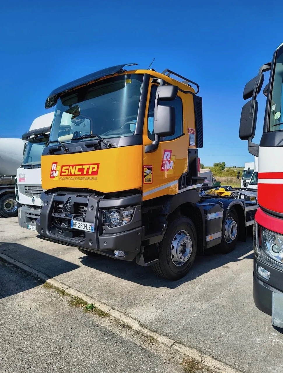 Camion de transport routier Renault avec logo SNCPT, stationné sur un parking en plein jour.