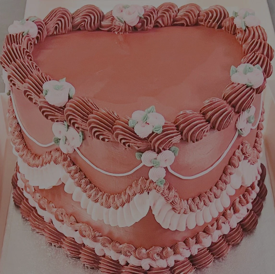 Red and pink heart-shaped celebration cake with vintage buttercream piping and floral details