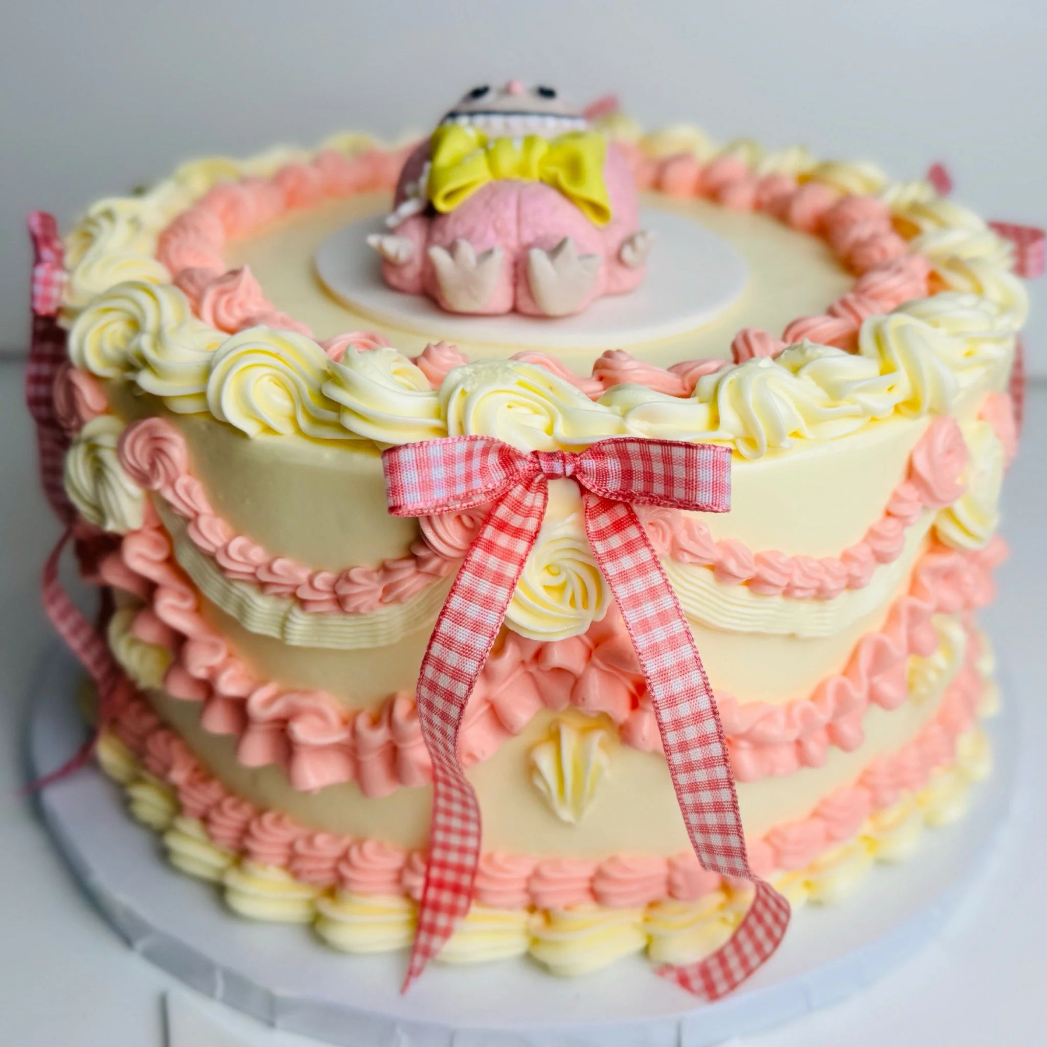 Pink and ivory bespoke heart-shaped cake with vintage piping and gingham bows
