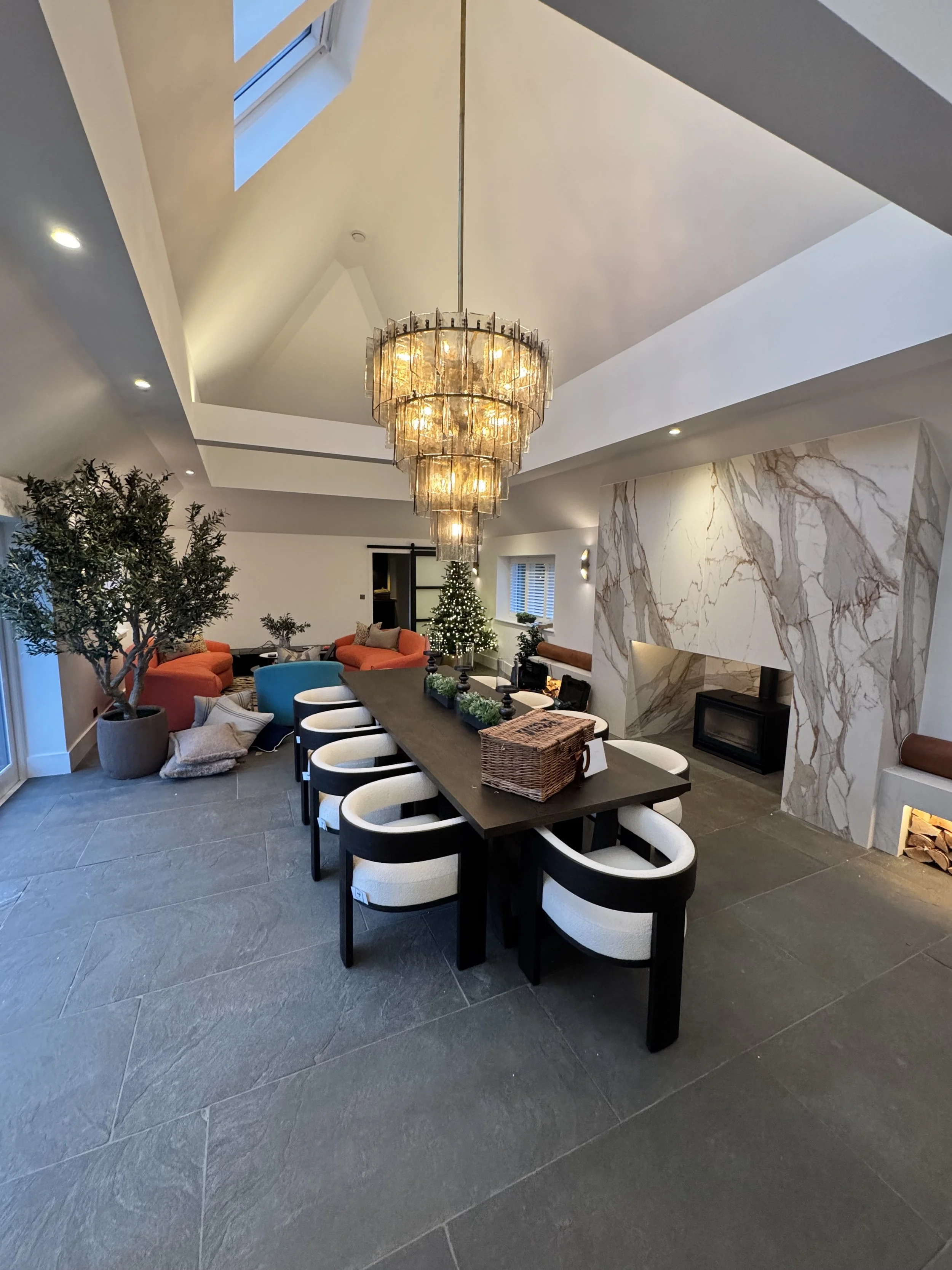 pacious open-plan dining area with high vaulted ceiling, skylights, freshly painted walls, statement chandelier and marble fireplace.