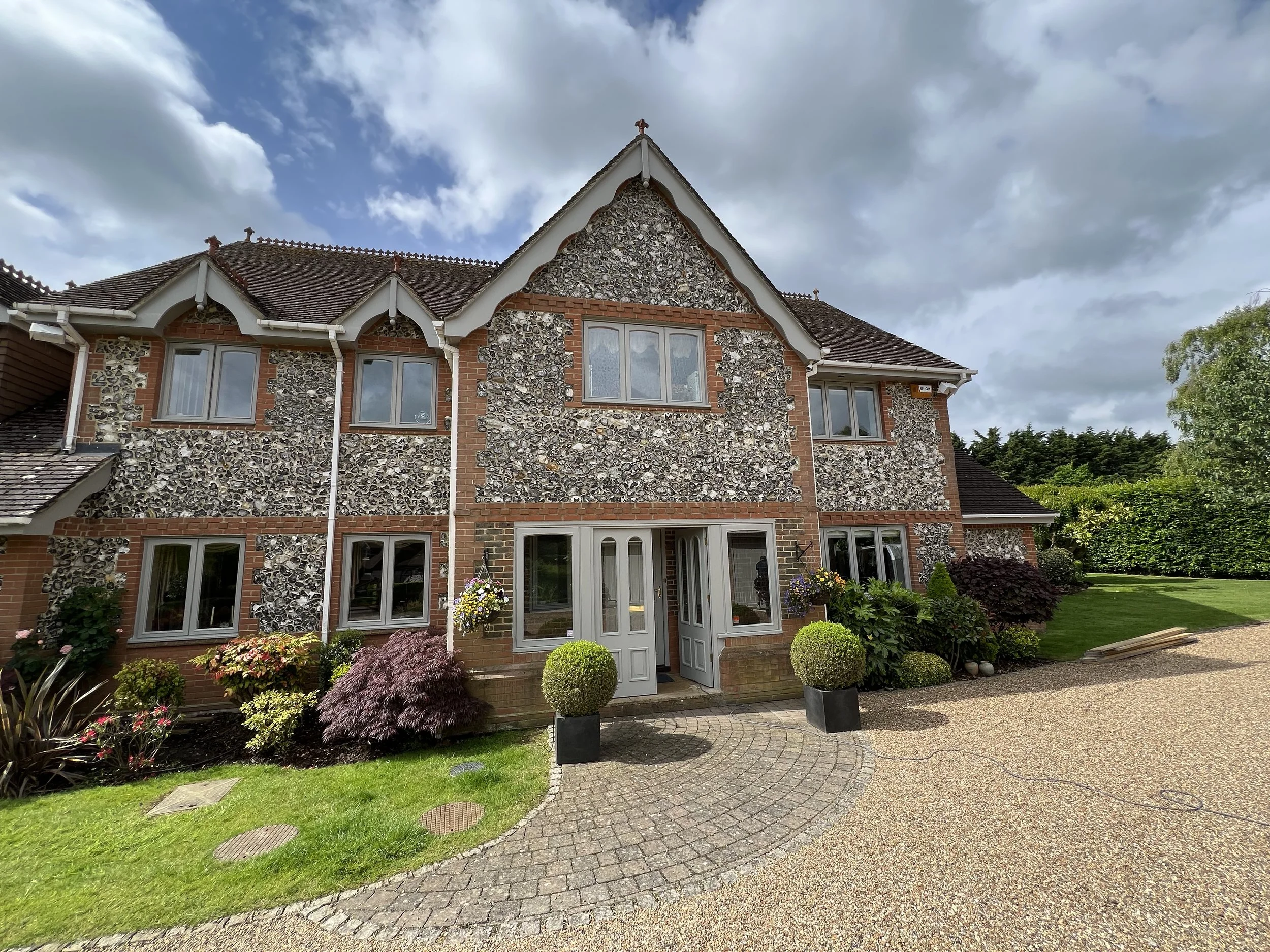 Exterior of a large detached house, high-quality exterior painting and decorating on a large detached house with flint and brick finish, clean window frames and front entrance.